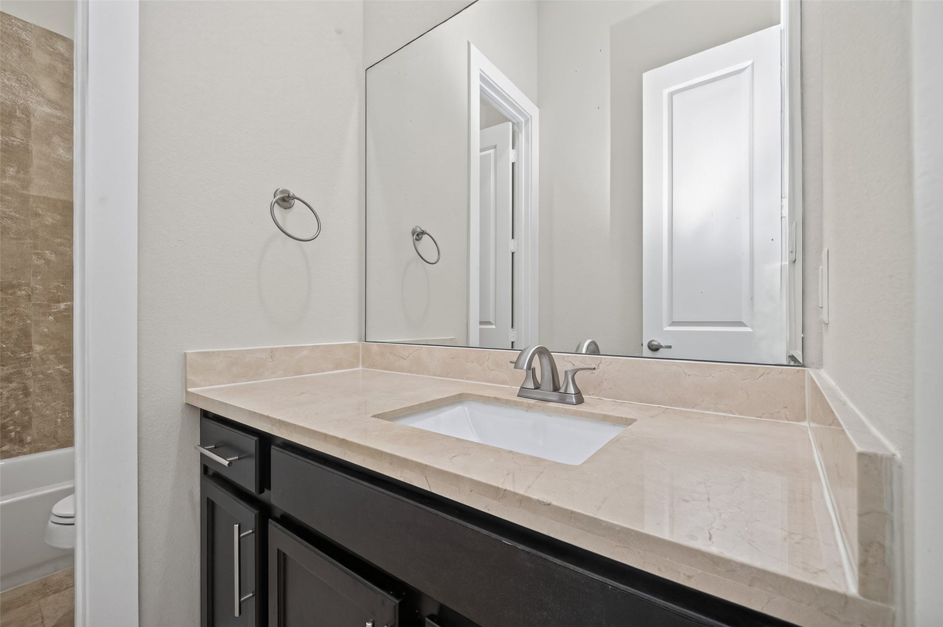 40 N Hutcheson Street, Houston, TX 77003 Modern bathroom featuring a sleek vanity with a polished marble countertop, elegant undermount sink, and chrome faucet, complemented by a large mirror and neutral tones.