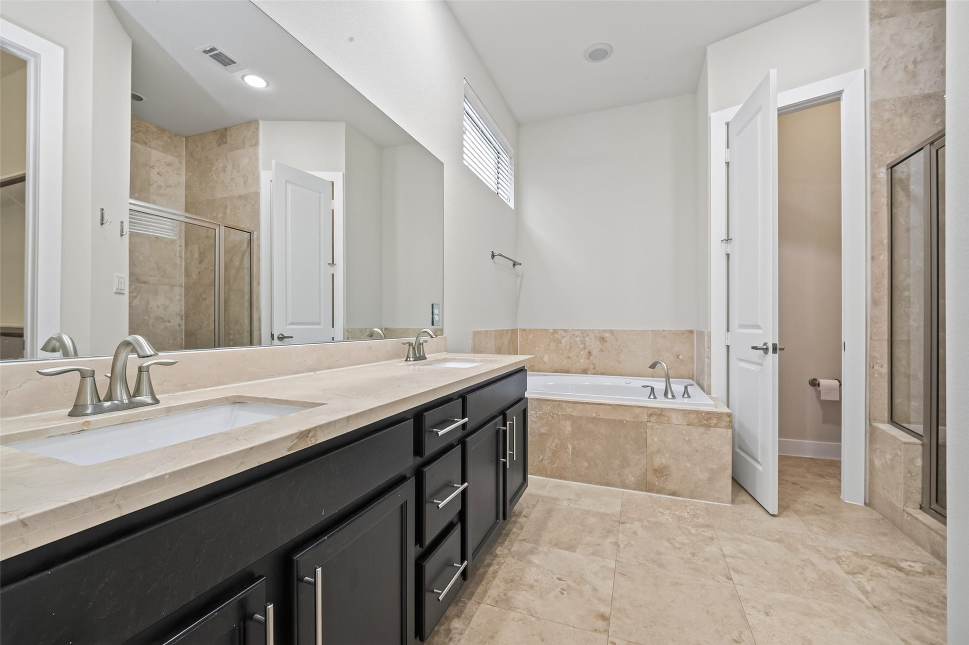 40 N Hutcheson Street, Houston, TX 77003 Luxurious bathroom featuring a double vanity with elegant fixtures, a spacious soaking tub, and a separate glass-enclosed shower, all accented with sleek tile flooring and modern finishes.