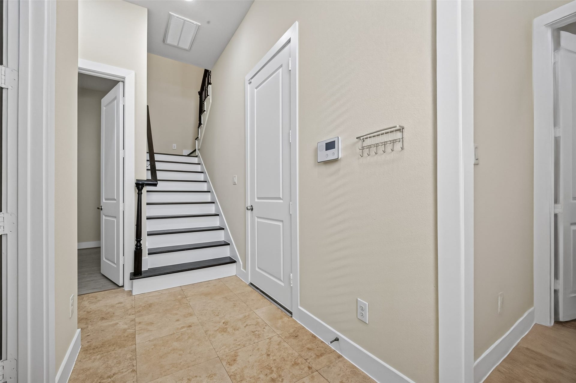 40 N Hutcheson Street, Houston, TX 77003 Inviting entryway with elegant tile flooring leads to a staircase featuring dark wood accents, complemented by neutral walls and modern finishes.
