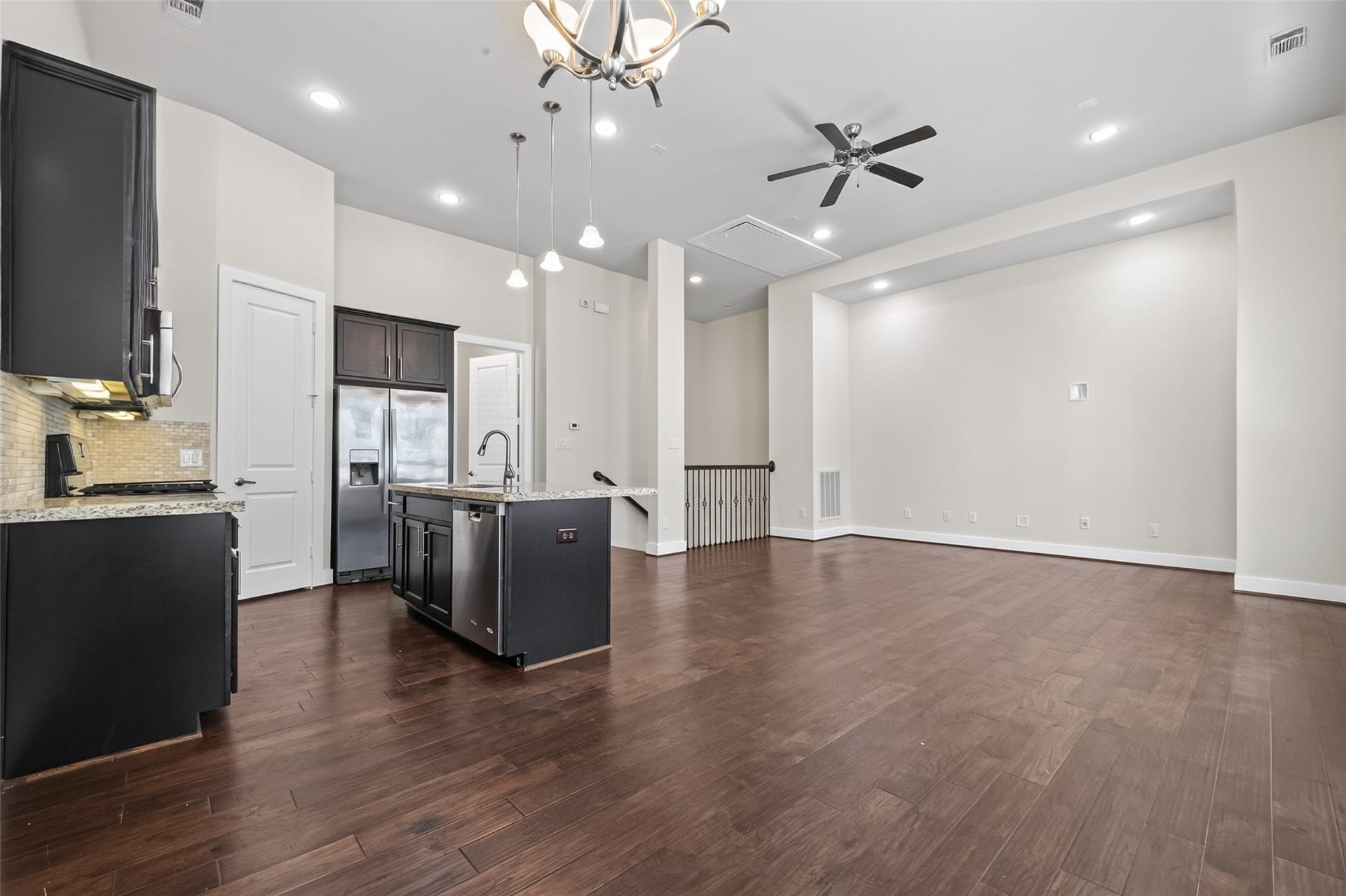 40 N Hutcheson Street, Houston, TX 77003 Spacious open-concept living area with elegant hardwood floors and a modern kitchen featuring dark cabinetry, granite countertops, and stainless steel appliances.