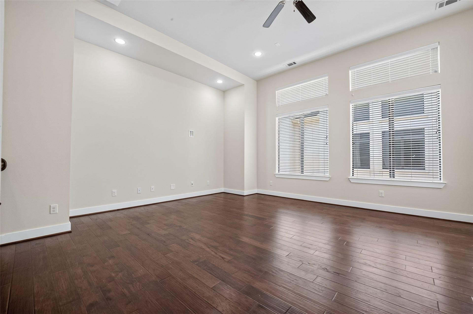 40 N Hutcheson Street, Houston, TX 77003 Spacious room with rich hardwood floors, large windows offering ample natural light, and modern recessed lighting.