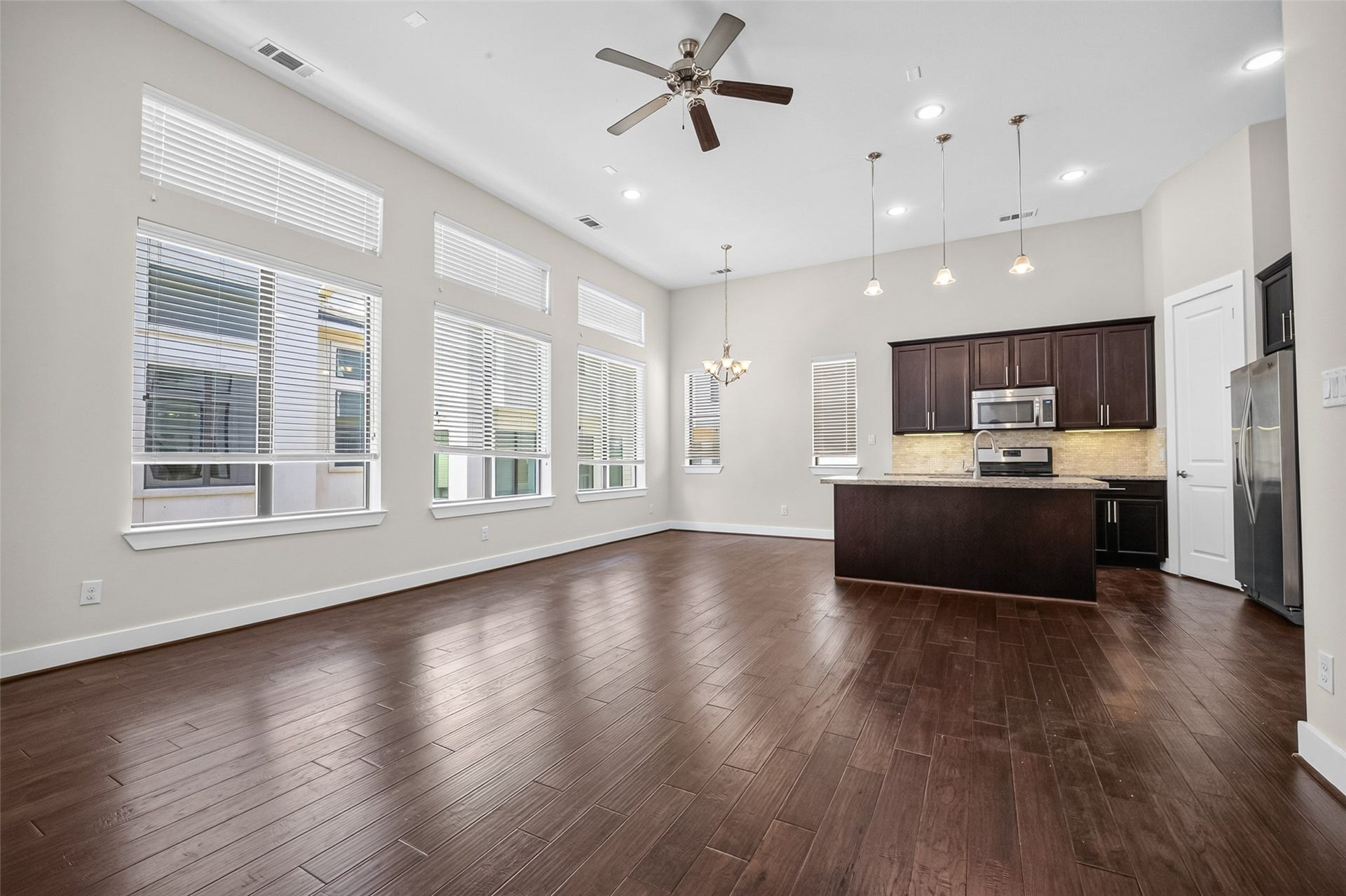 40 N Hutcheson Street, Houston, TX 77003 Spacious open-concept living area with high ceilings, abundant natural light from large windows, and a modern kitchen featuring dark cabinetry, stainless steel appliances, and a central island with pendant lighting.