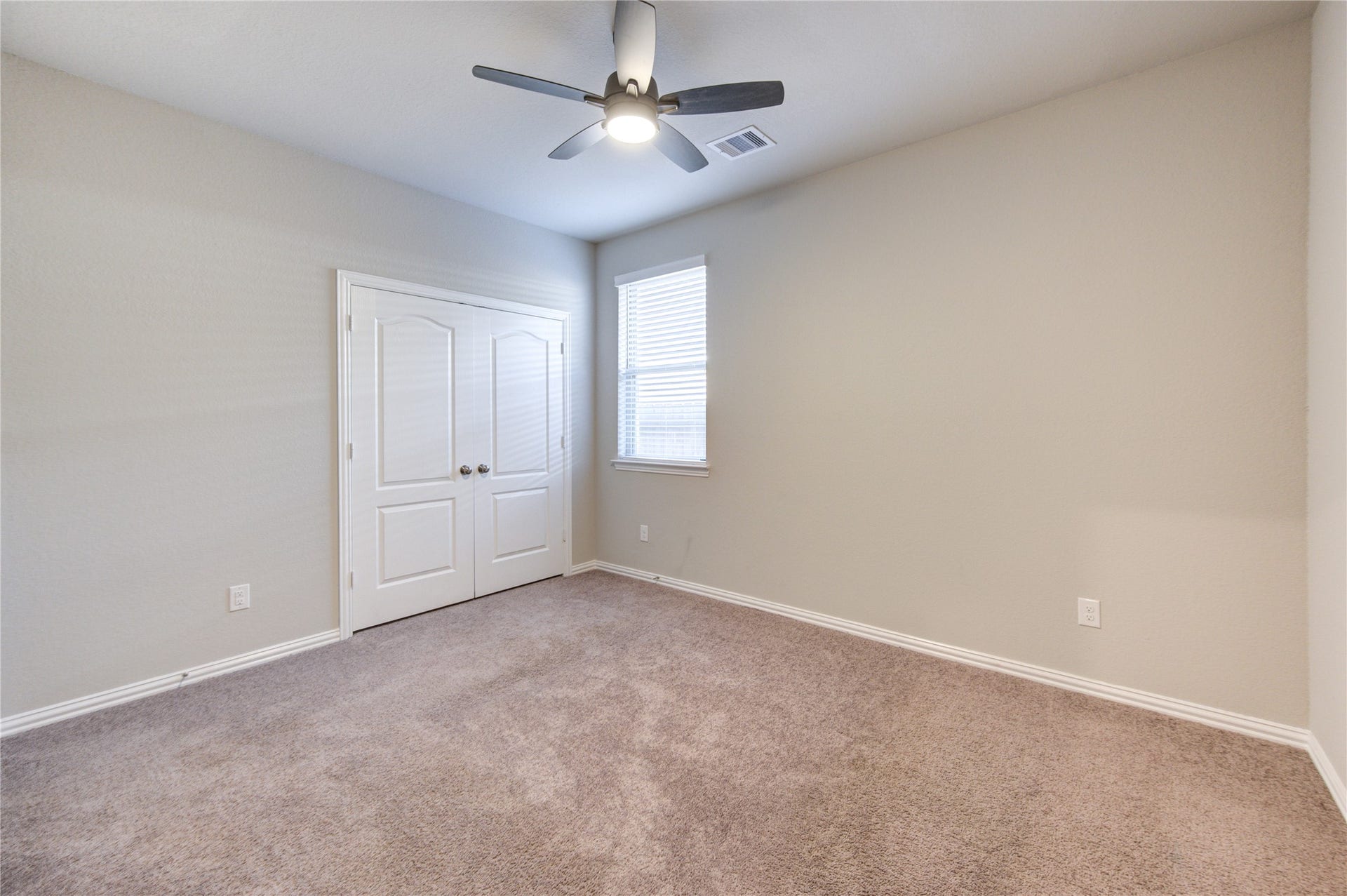 Spacious secondary bedroom with ceiling fan and plenty of natural light
