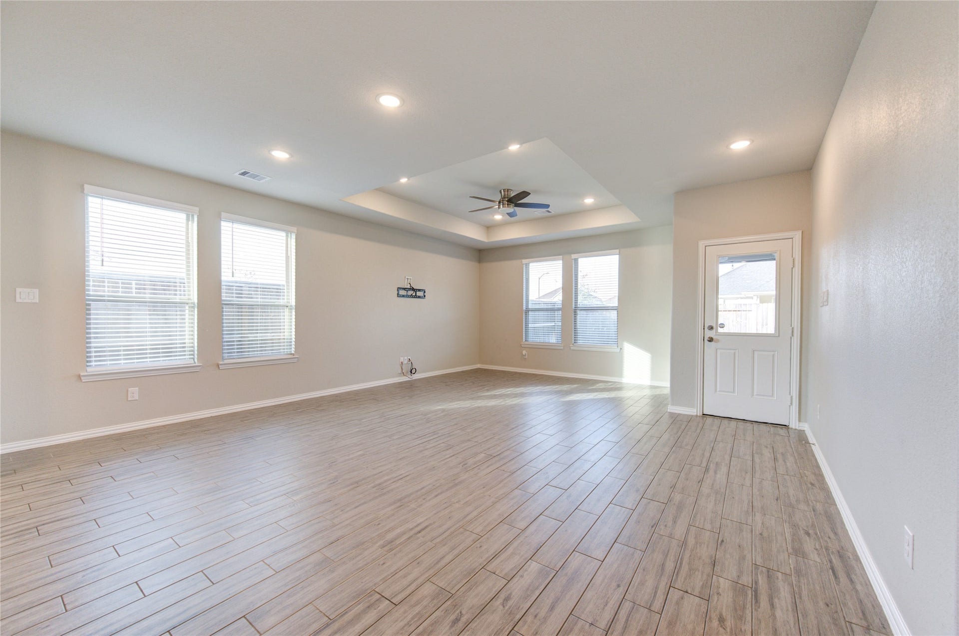 Spacious open-concept living area with abundant natural light, recessed lighting, and a ceiling fan