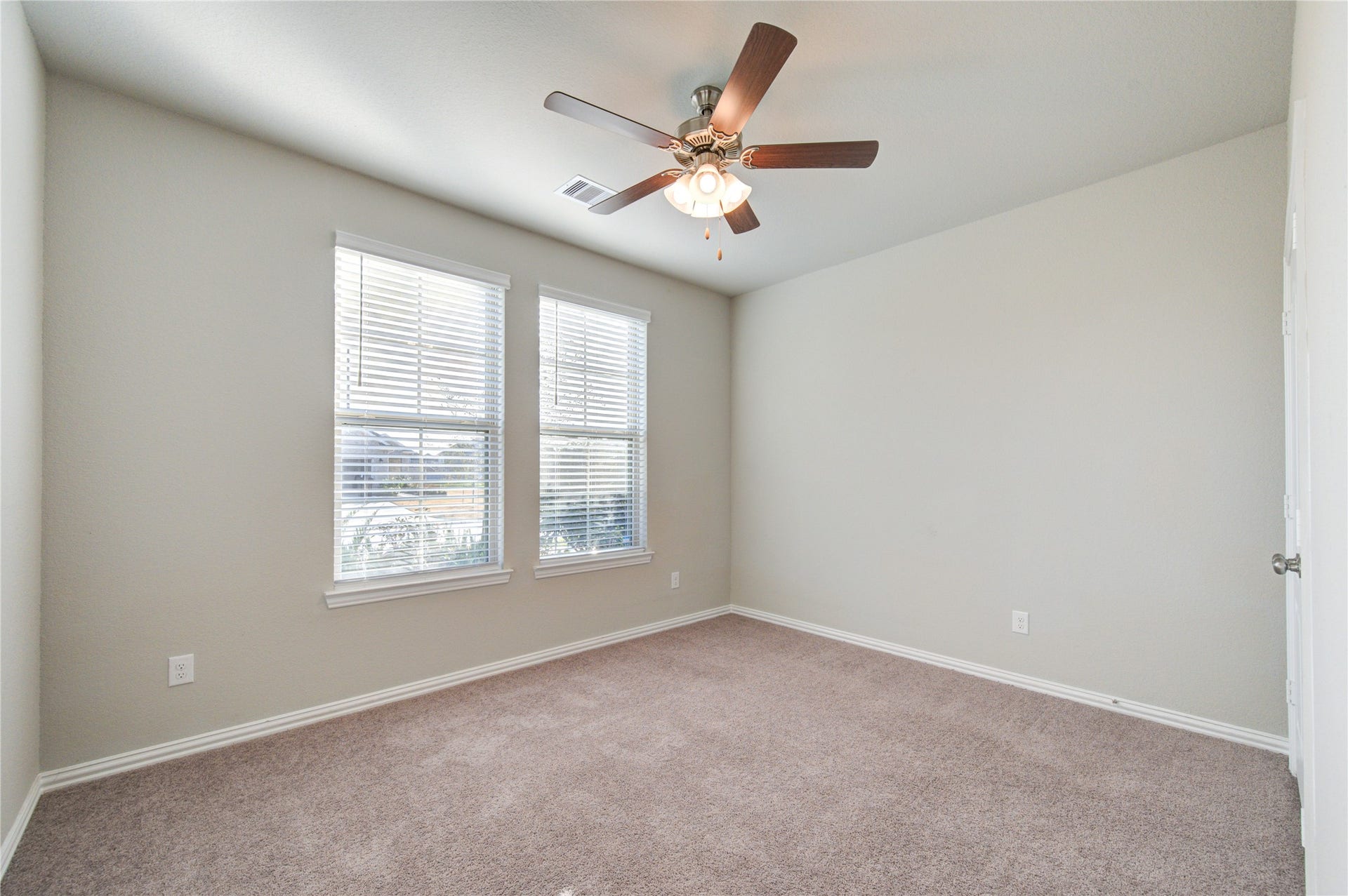 Spacious secondary bedroom with ceiling fan and natural light