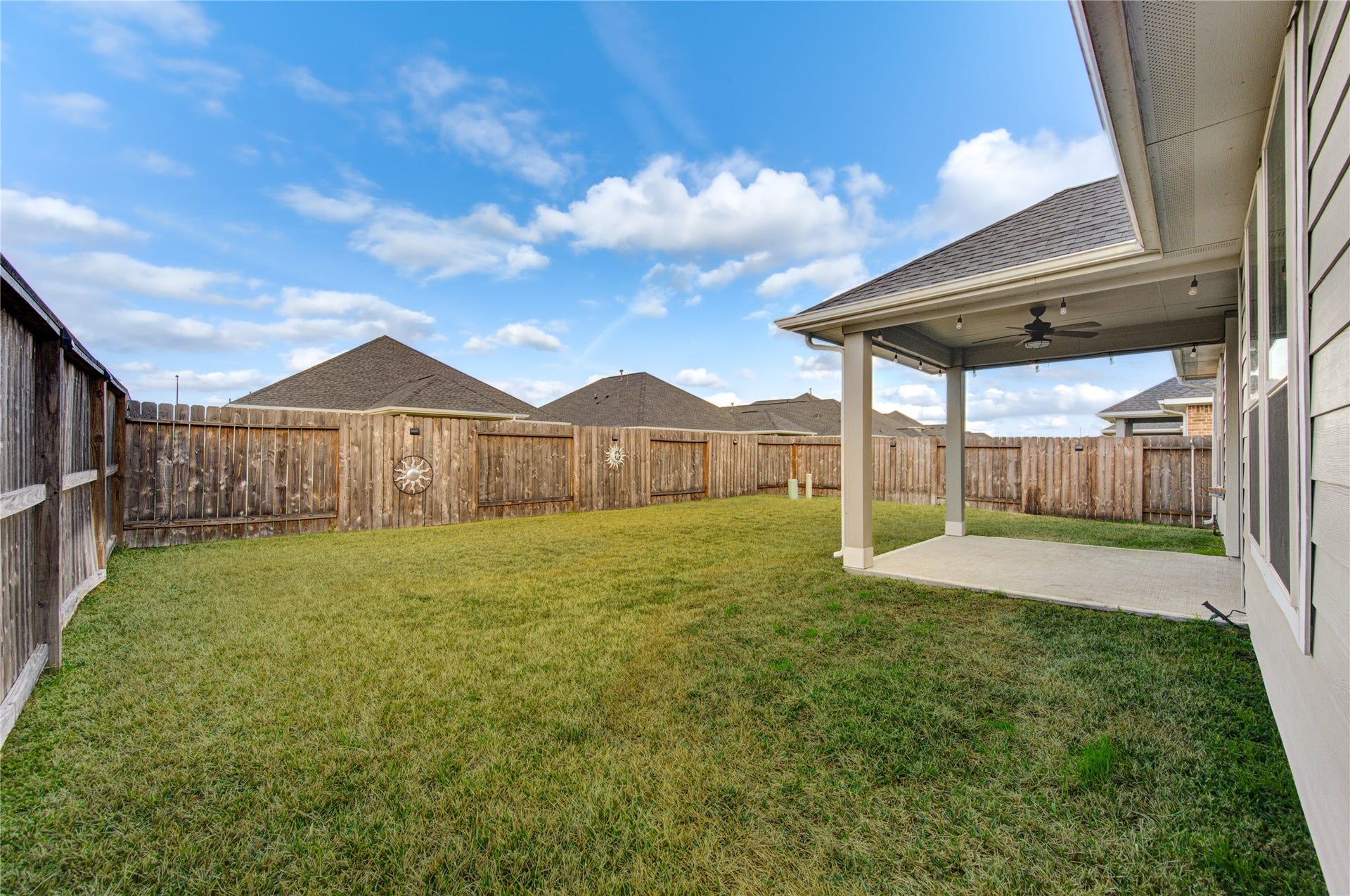 Fenced backyard with plenty of room to enjoy and a covered patio with ceiling fans