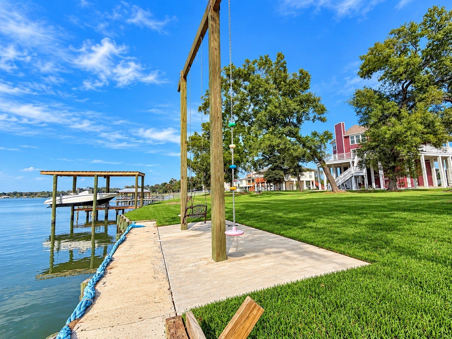 Lakeside living at its finest with a private boat dock, lush lawn, and a charming swing set, perfect for relaxing by the water.