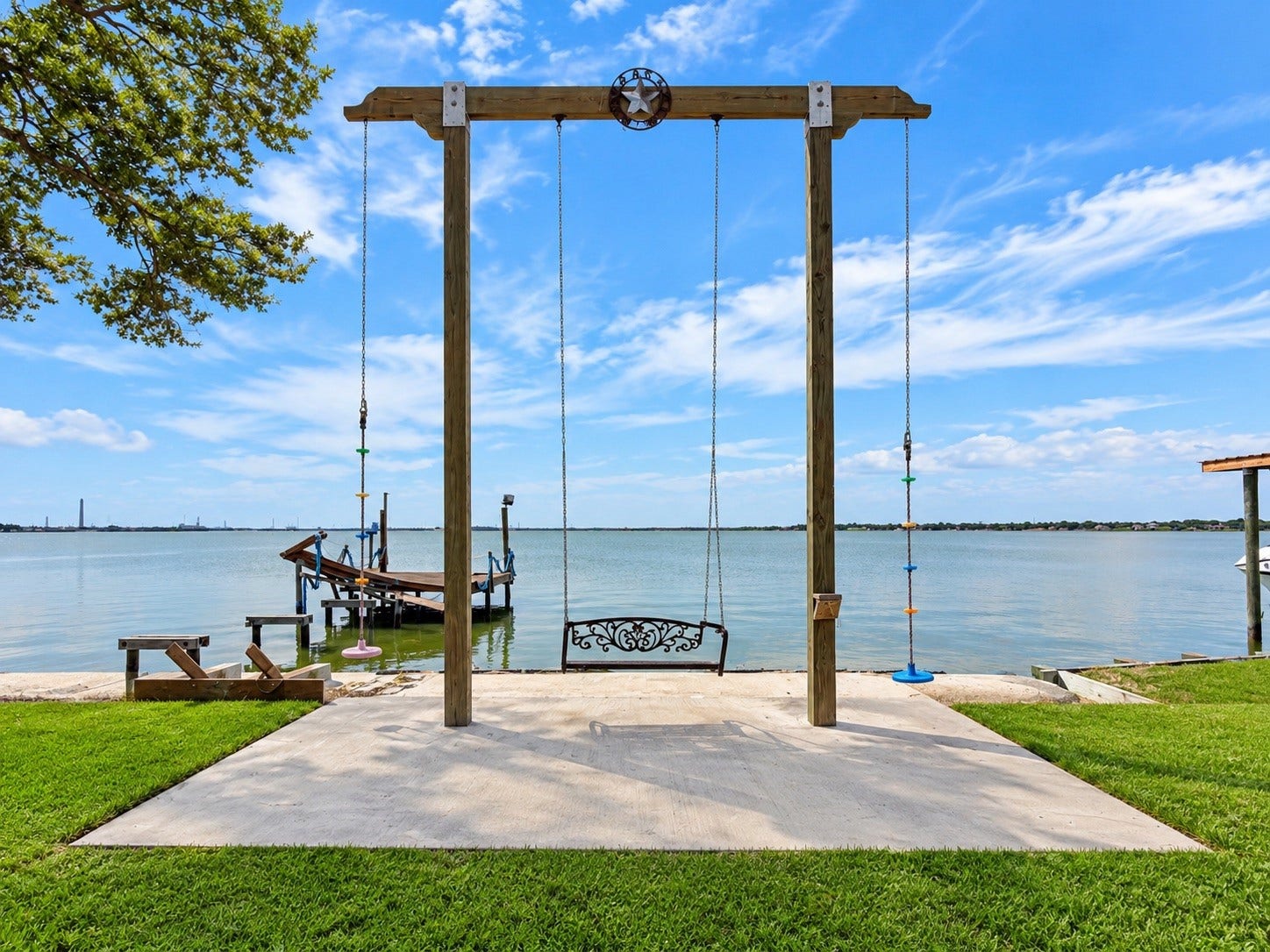 Serene lakeside retreat featuring a charming swing set on a spacious concrete patio, perfect for relaxation with stunning water views.