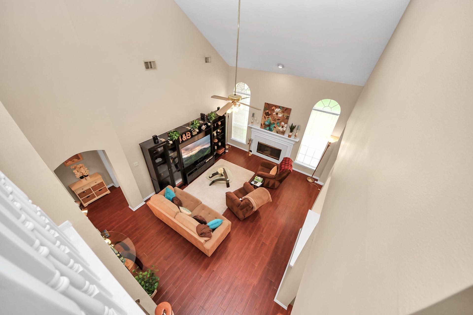 7015 Morningside Drive, Sugar Land, TX 77479 Experience the elegance of this spacious living room with soaring ceilings, rich hardwood floors, and abundant natural light from large arched windows.