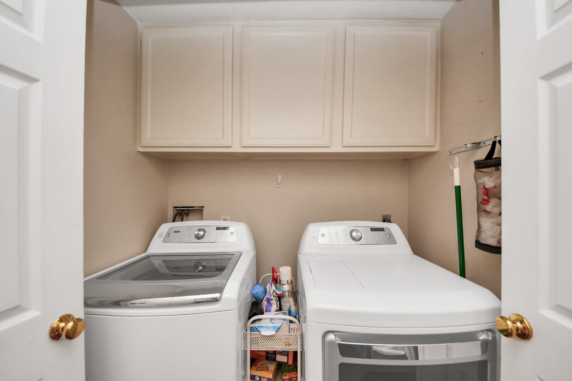 7015 Morningside Drive, Sugar Land, TX 77479 Efficient laundry area featuring modern washer and dryer, ample overhead storage cabinets, and convenient utility shelving.