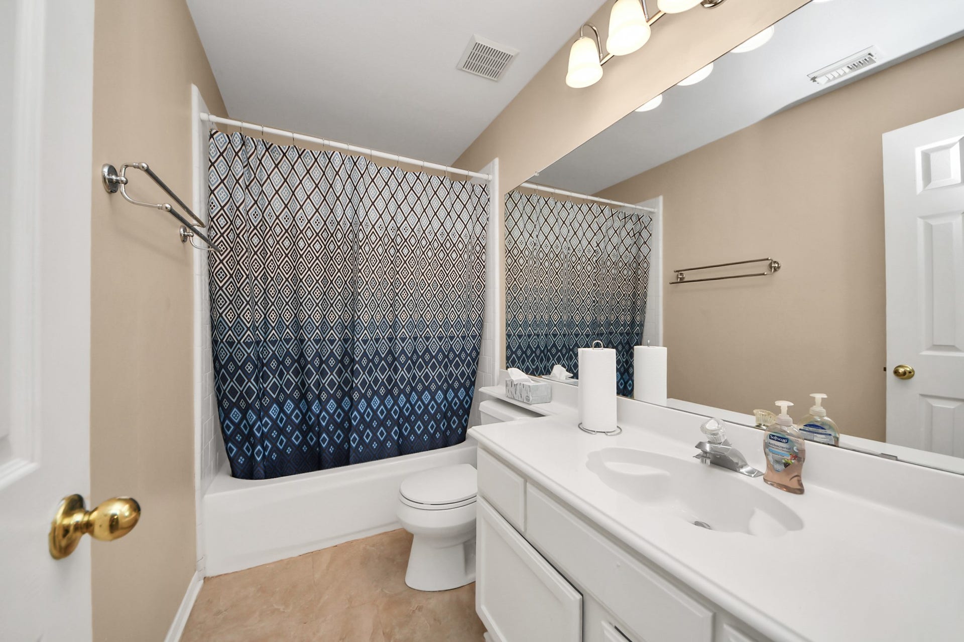 7015 Morningside Drive, Sugar Land, TX 77479 Bright bathroom featuring a sleek white vanity, ample counter space, and a stylish blue patterned shower curtain.