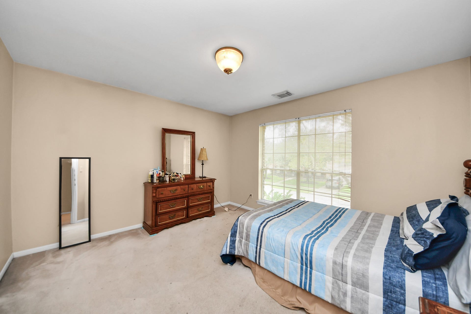 7015 Morningside Drive, Sugar Land, TX 77479 Spacious bedroom featuring a large window that fills the room with natural light, complemented by neutral walls and cozy carpeting.