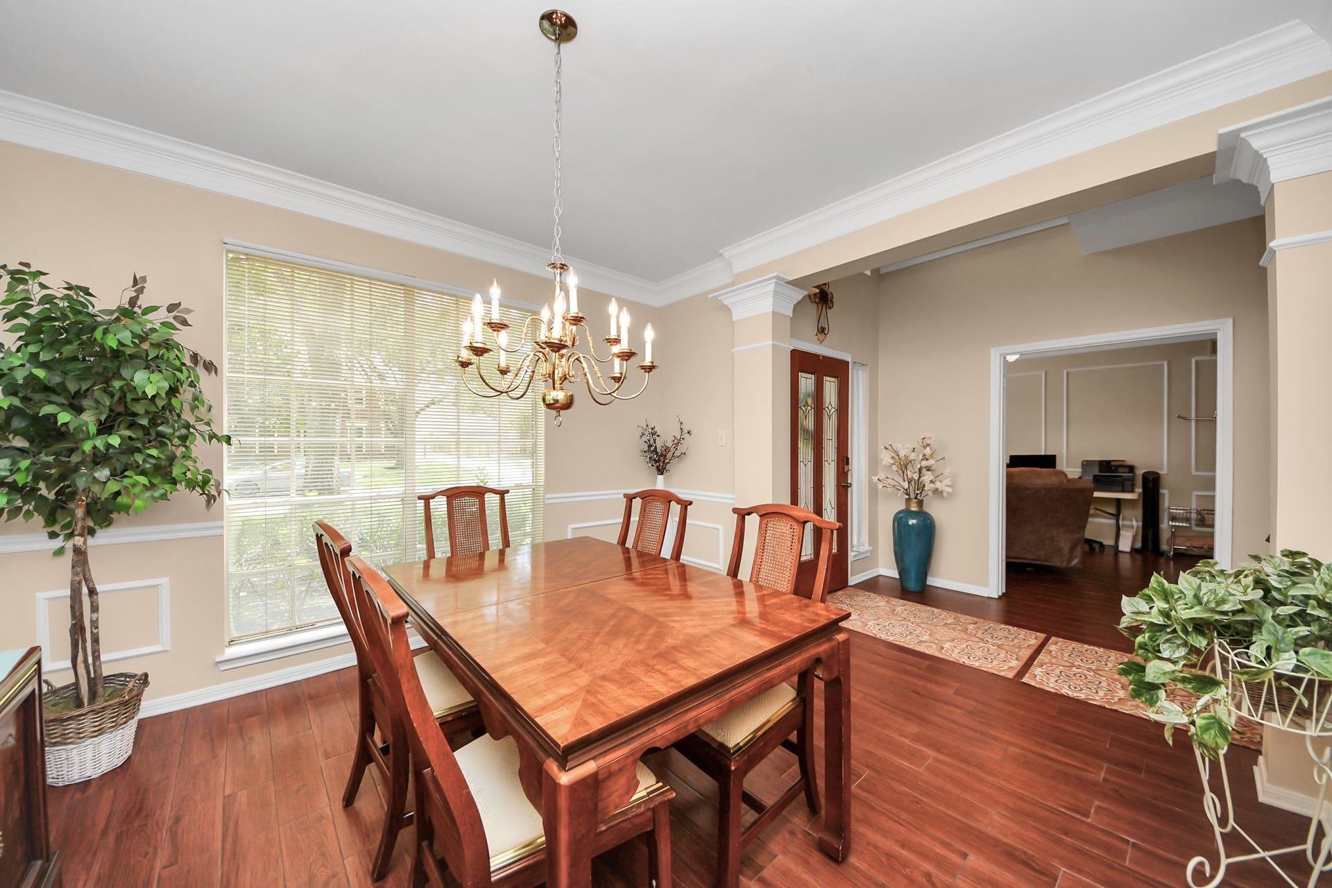7015 Morningside Drive, Sugar Land, TX 77479 Elegant dining room featuring a classic chandelier, rich wood floors, and large windows that fill the space with natural light.