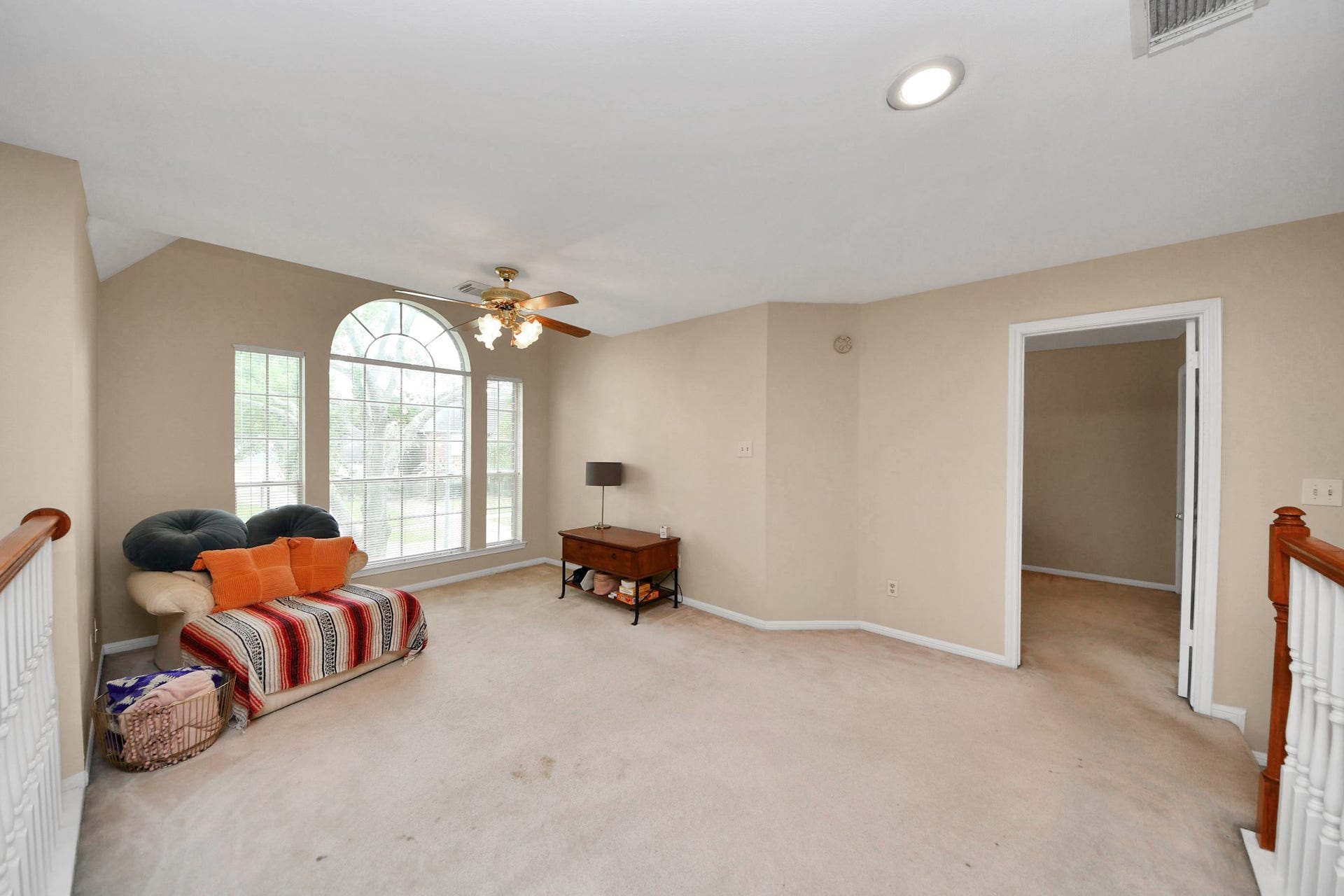 7015 Morningside Drive, Sugar Land, TX 77479 Spacious room with a large arched window, cozy seating area, and neutral tones, offering a versatile living space.