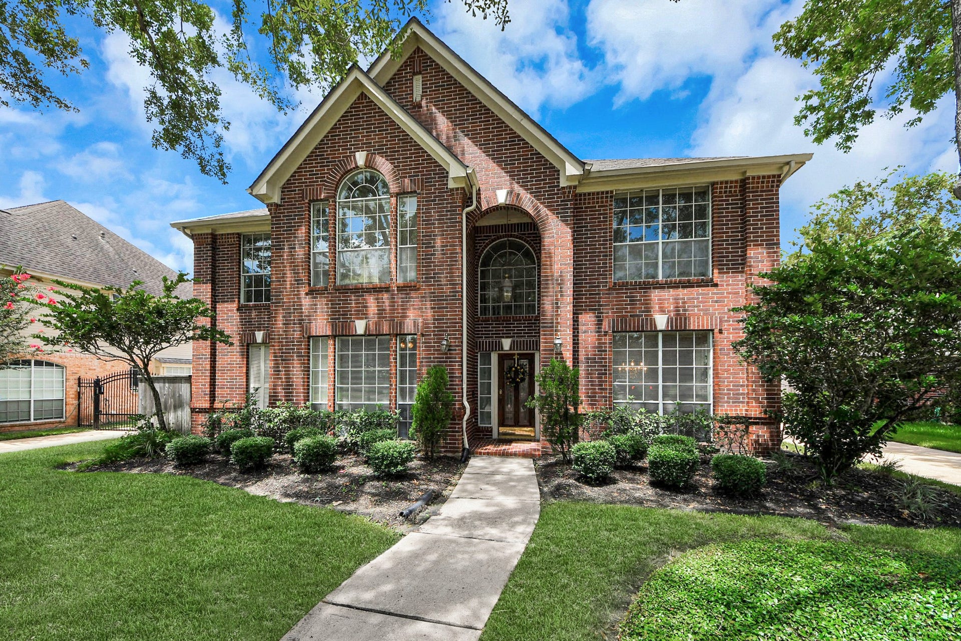 7015 Morningside Drive, Sugar Land, TX 77479 Stunning brick facade with large arched windows and lush landscaping, offering timeless curb appeal.