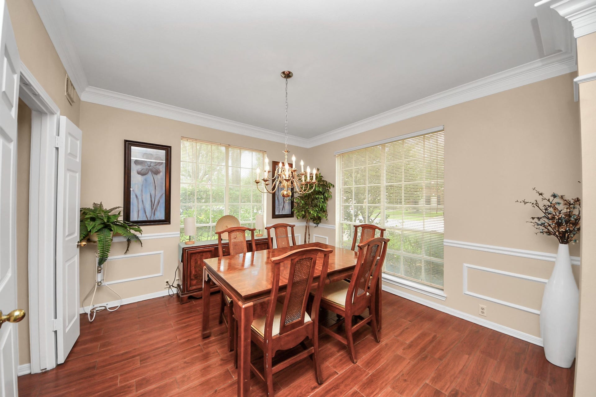 7015 Morningside Drive, Sugar Land, TX 77479 Elegant dining room with rich hardwood floors, abundant natural light from large windows, and classic crown molding, perfect for entertaining.