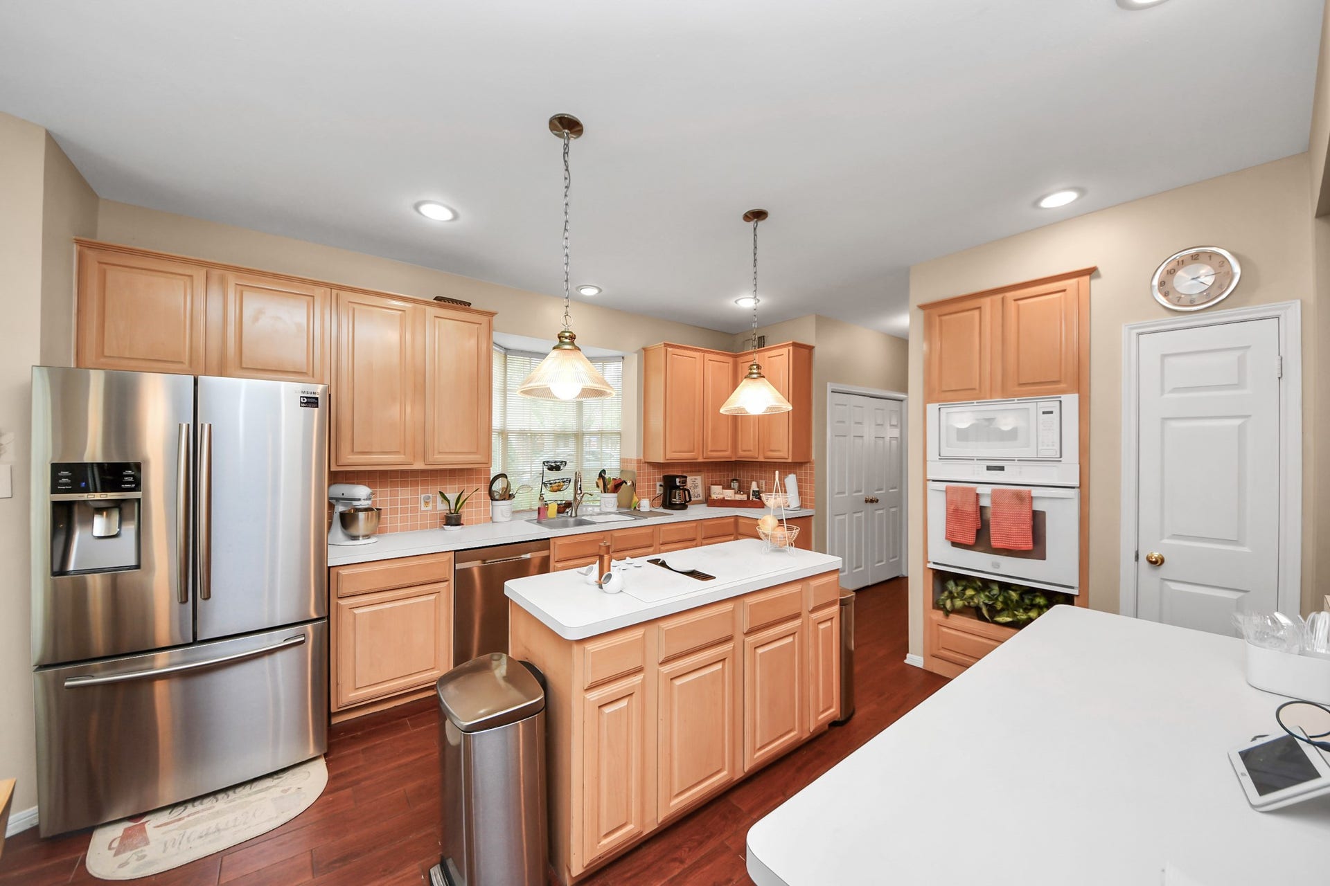 7015 Morningside Drive, Sugar Land, TX 77479 Spacious kitchen featuring modern stainless steel appliances, warm wood cabinetry, a central island with pendant lighting, and ample counter space for culinary enthusiasts.