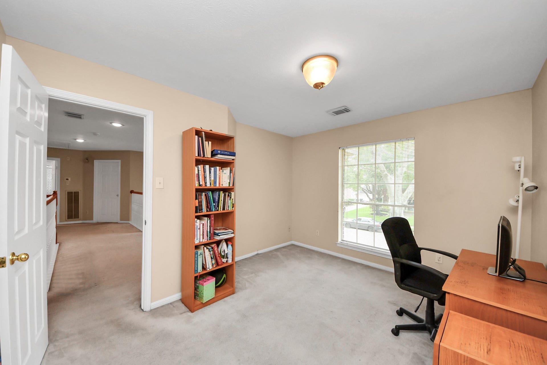 7015 Morningside Drive, Sugar Land, TX 77479 Bright home office with natural light, featuring a cozy desk setup and built-in shelving, perfect for productivity.