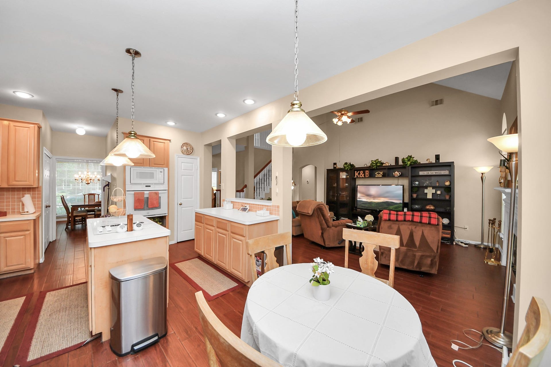 7015 Morningside Drive, Sugar Land, TX 77479 Spacious open-concept kitchen and living area featuring warm wood floors, ample cabinetry, and cozy seating for relaxation and dining.