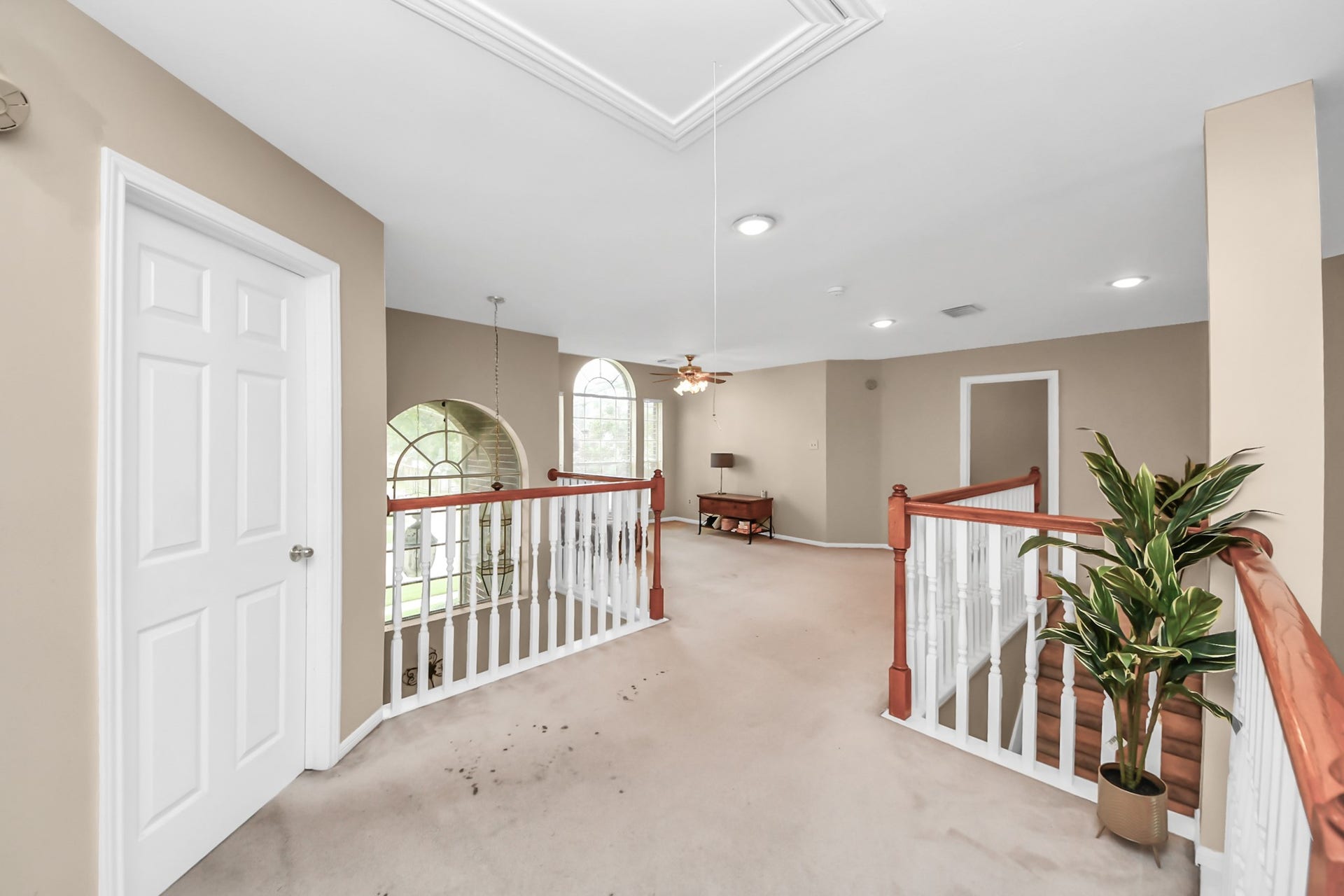 7015 Morningside Drive, Sugar Land, TX 77479 Spacious upper-level landing with elegant white railing, featuring ample natural light from large arched windows, and access to multiple rooms.