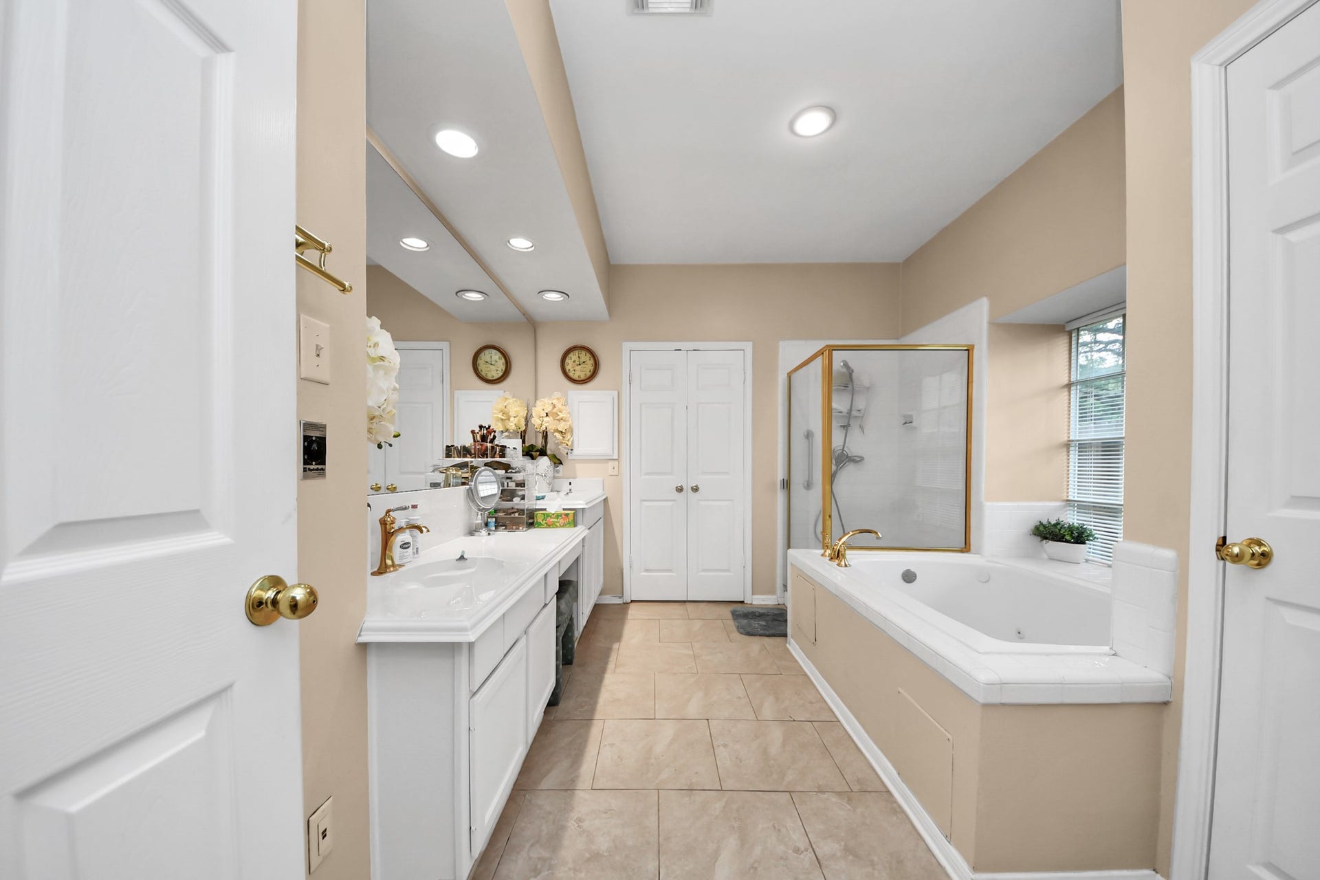 7015 Morningside Drive, Sugar Land, TX 77479 Spacious bathroom featuring a luxurious corner bathtub, a separate glass-enclosed shower, and dual vanities with ample counter space, all accented by soft lighting and elegant fixtures.