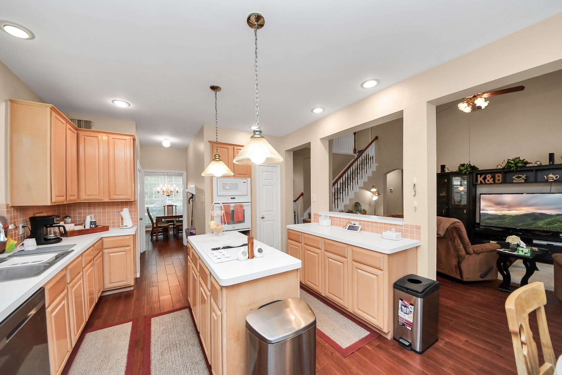 7015 Morningside Drive, Sugar Land, TX 77479 Spacious kitchen with warm wood cabinetry, modern appliances, and a central island, seamlessly connecting to a cozy living area and a formal dining space.