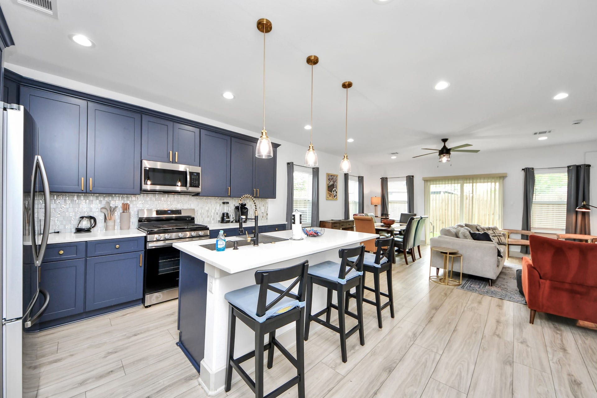 837 W Little York Road, Houston, TX 77091 Bright open-concept kitchen with deep blue cabinetry, stainless steel appliances, large center island, and pendant lighting.