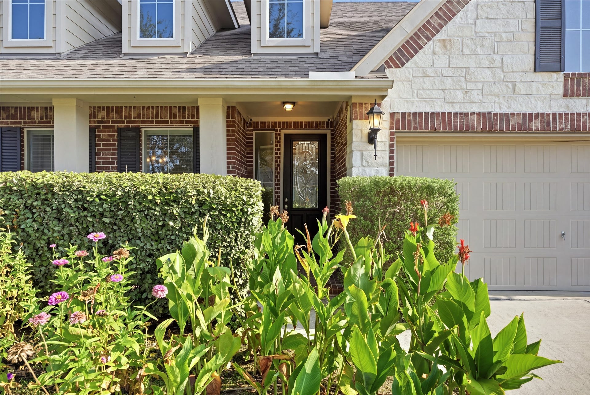 1717 Oakdale Mist Drive, Dickinson, TX 77539 The covered front porch is surrounded by lush landscaping and leads to a decorative glass front door, creating an inviting entrance to the home.
