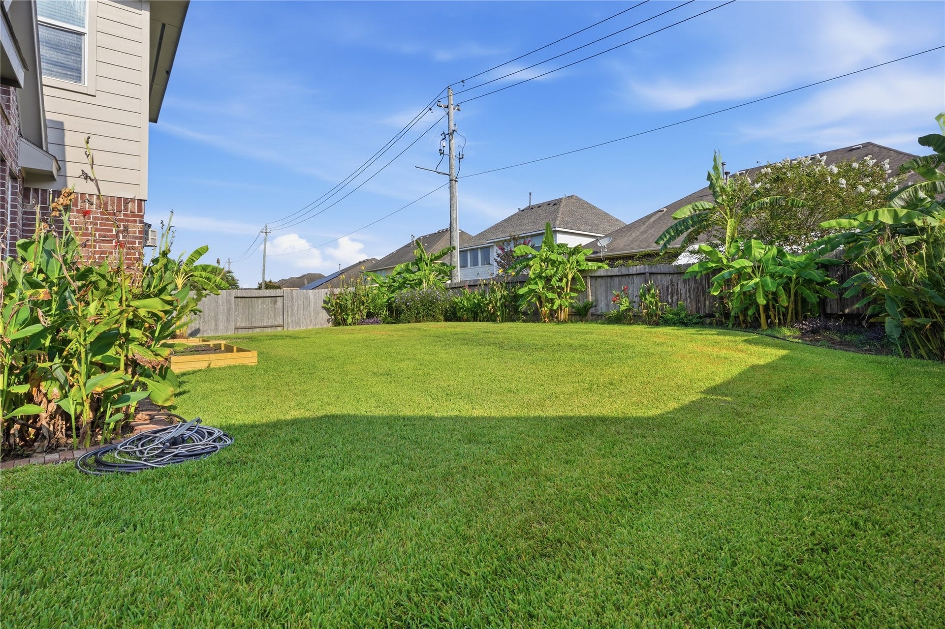 1717 Oakdale Mist Drive, Dickinson, TX 77539 Another view of the backyard highlights the open lawn, established tropical landscaping, and plenty of outdoor space to enjoy.