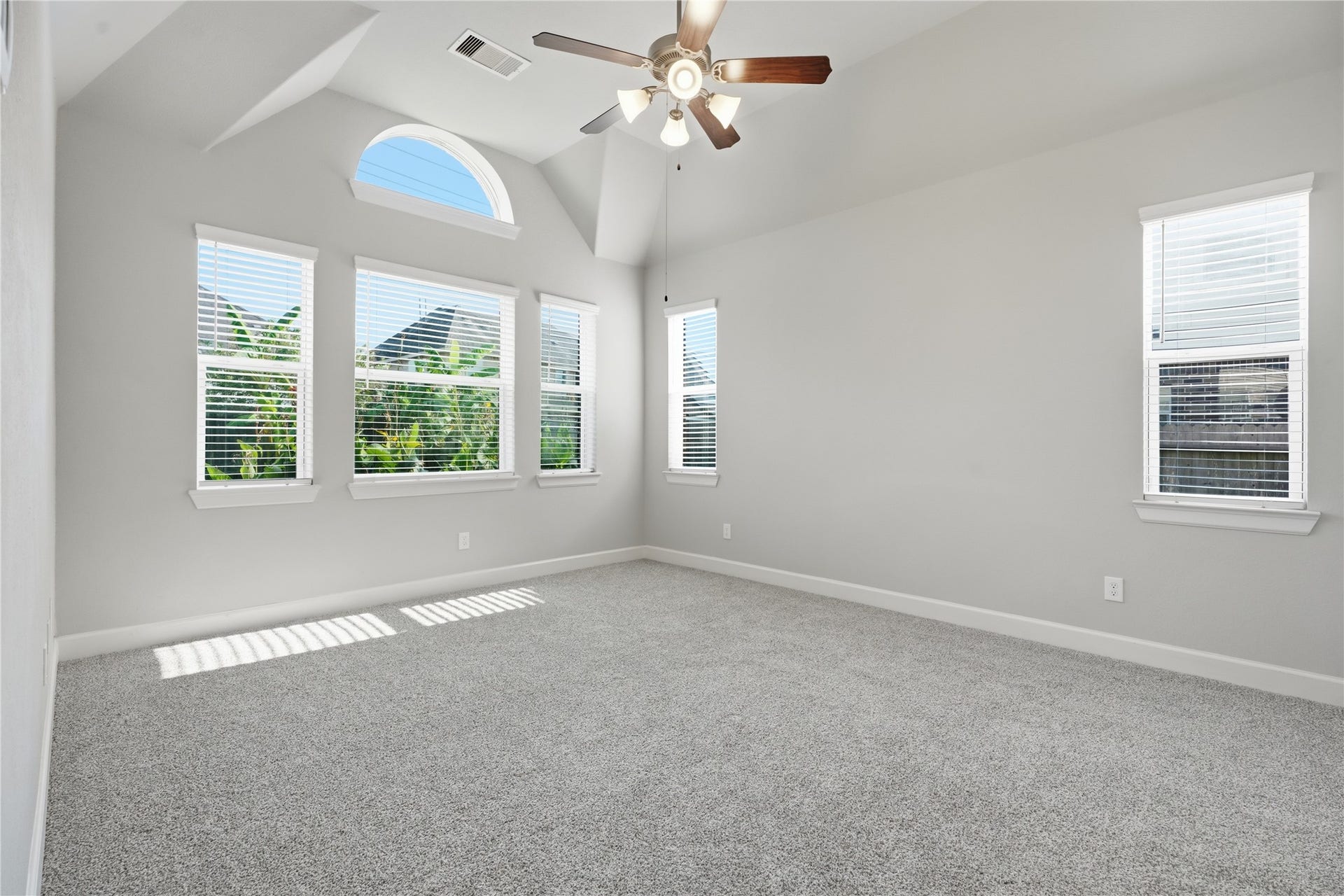 1717 Oakdale Mist Drive, Dickinson, TX 77539 Spacious primary bedroom featuring carpet replaced in August 2026 and a wall of windows that fills the room with natural light and offers views of the backyard.