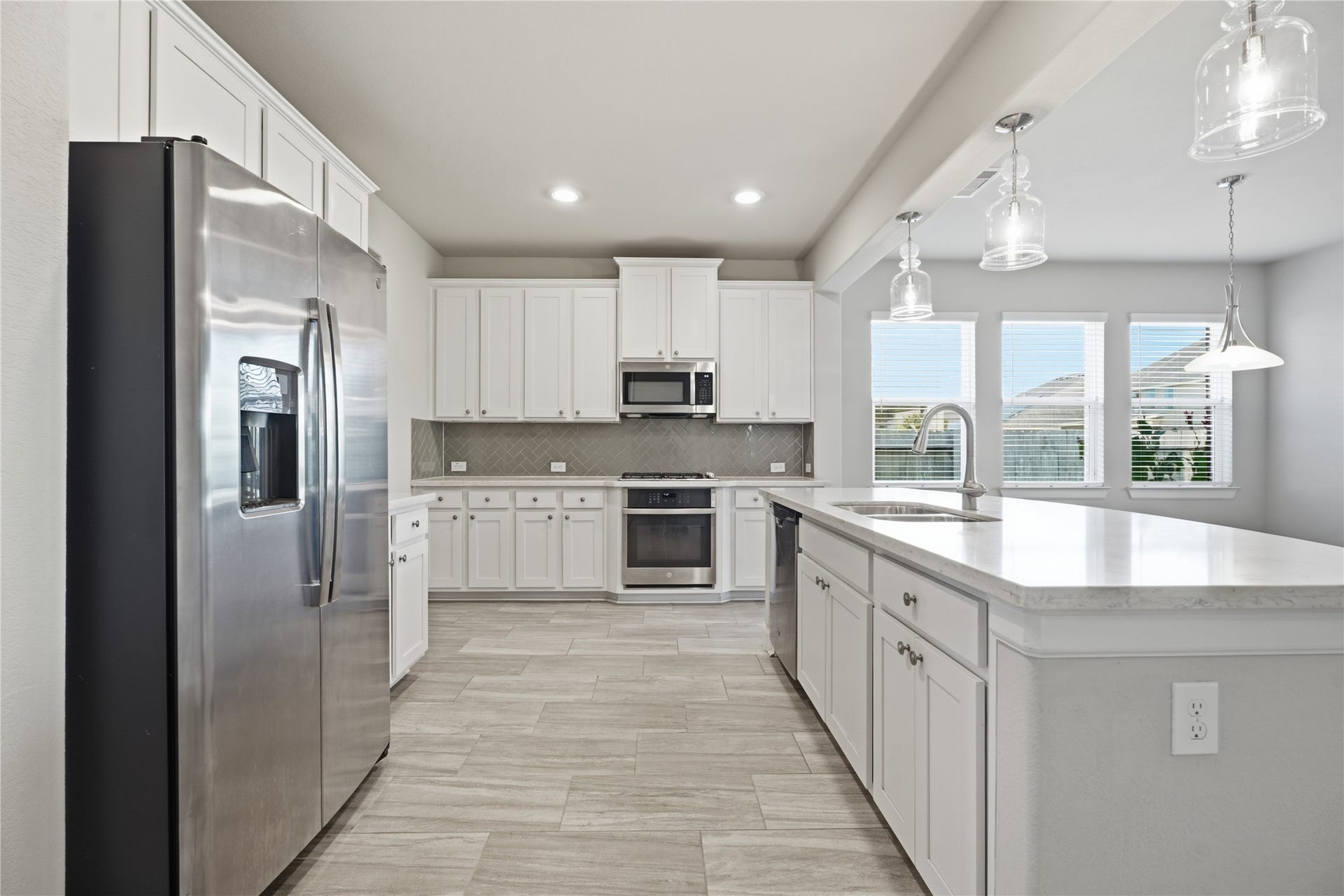 1717 Oakdale Mist Drive, Dickinson, TX 77539 The kitchen flows seamlessly into the breakfast area, with large windows bringing in natural light and offering views of the backyard.