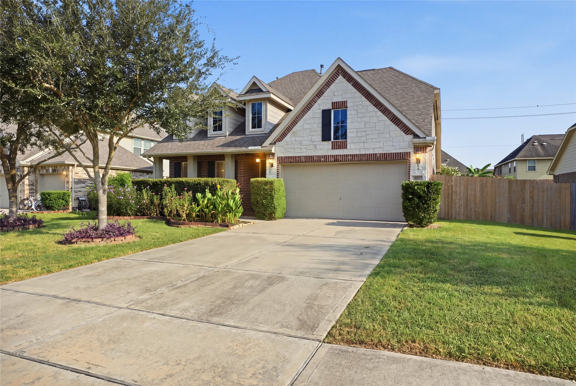 1717 Oakdale Mist Drive, Dickinson, TX 77539 A closer look at the homes inviting exterior, featuring a spacious driveway, two-car garage, mature landscaping, and a covered front porch.