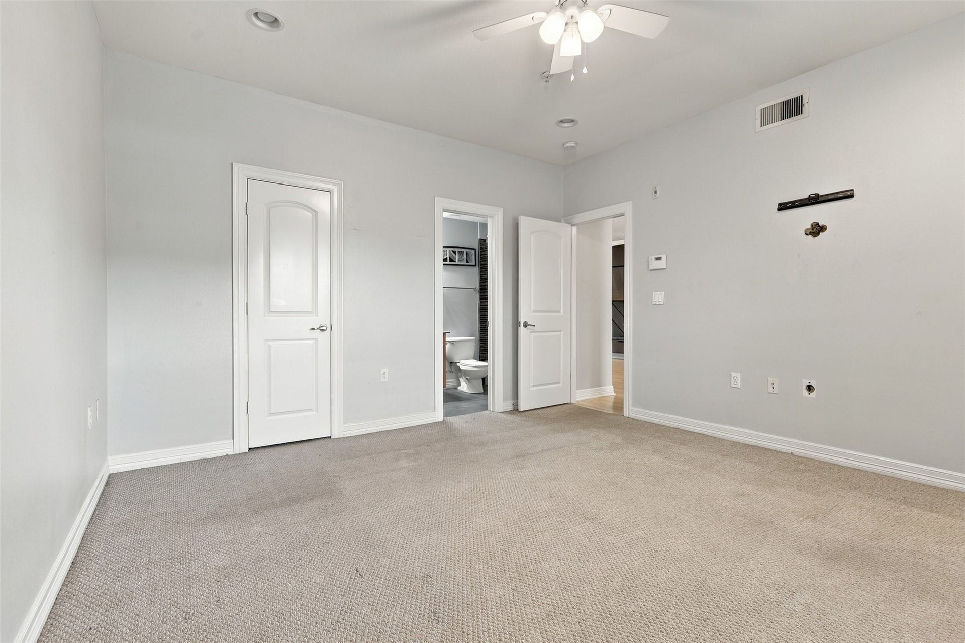 3501 Chenevert Street, #3, Houston, TX 77004 Spacious bedroom with neutral walls and carpet, featuring a ceiling fan and en-suite bathroom access for added convenience.
