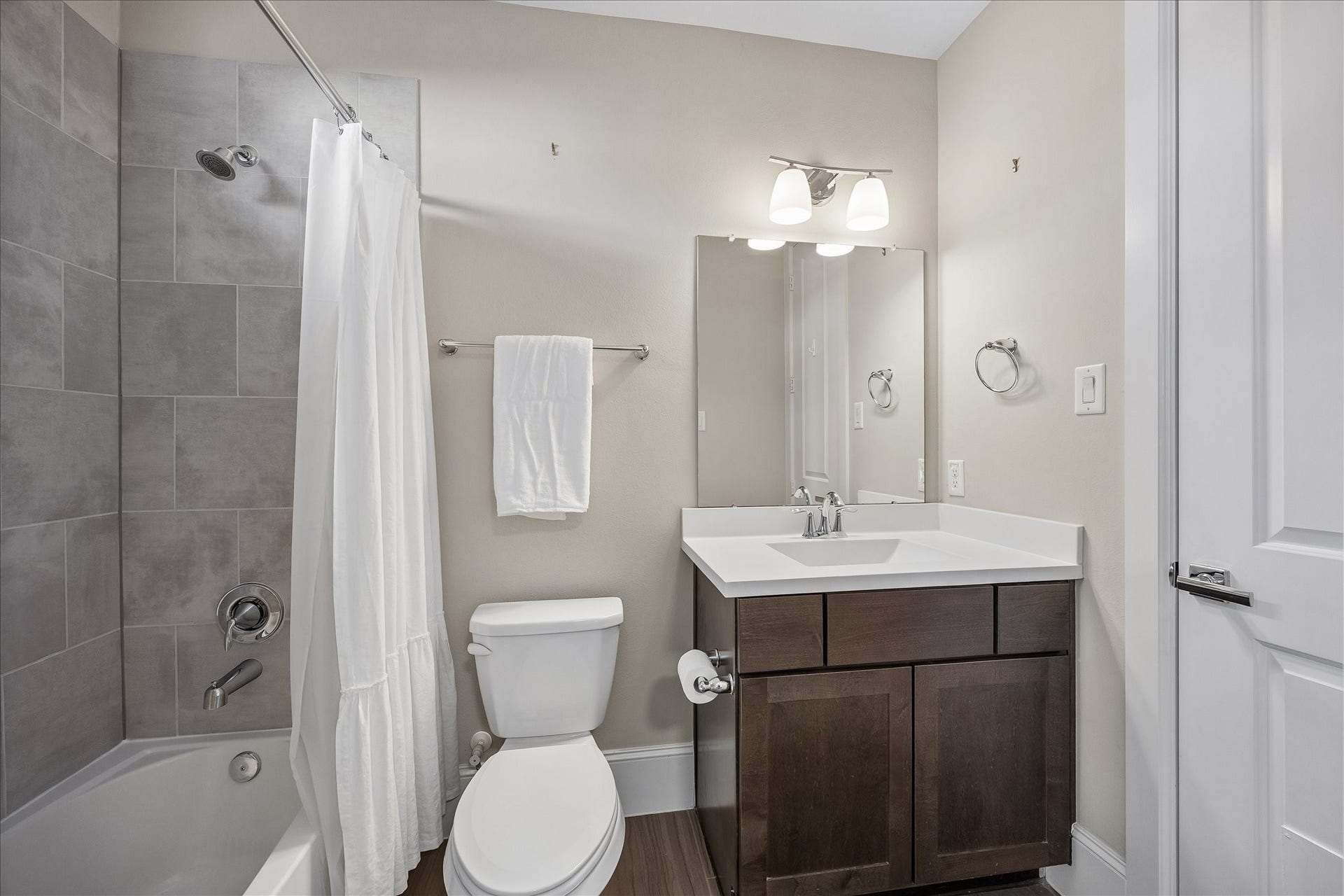 Private en suite bath serving the 1st floor secondary bedroom features a vanity w/ storage below, decorative vanity lighting & shower/tub combination w/ built-in soap niche. Privacy window provides natural light, while adjoining walk-in closet offers built-in hanging space. Wonderful functionality for guests or everyday use!