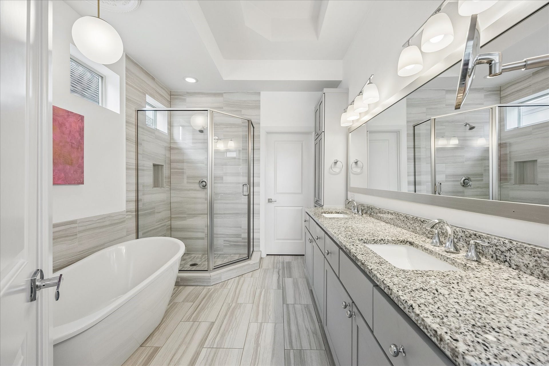 Dreamy primary bath featuring expansive vanity w/ dual sinks, beautiful granite countertops & abundant cabinetry for storage! Decorative vanity lighting & large mirror enhance the thoughtfully designed space. Glass-front storage cabinets w/ additional cabinetry below provide excellent organization. Separate walk-in closet offers wonderful additional storage & functionality!