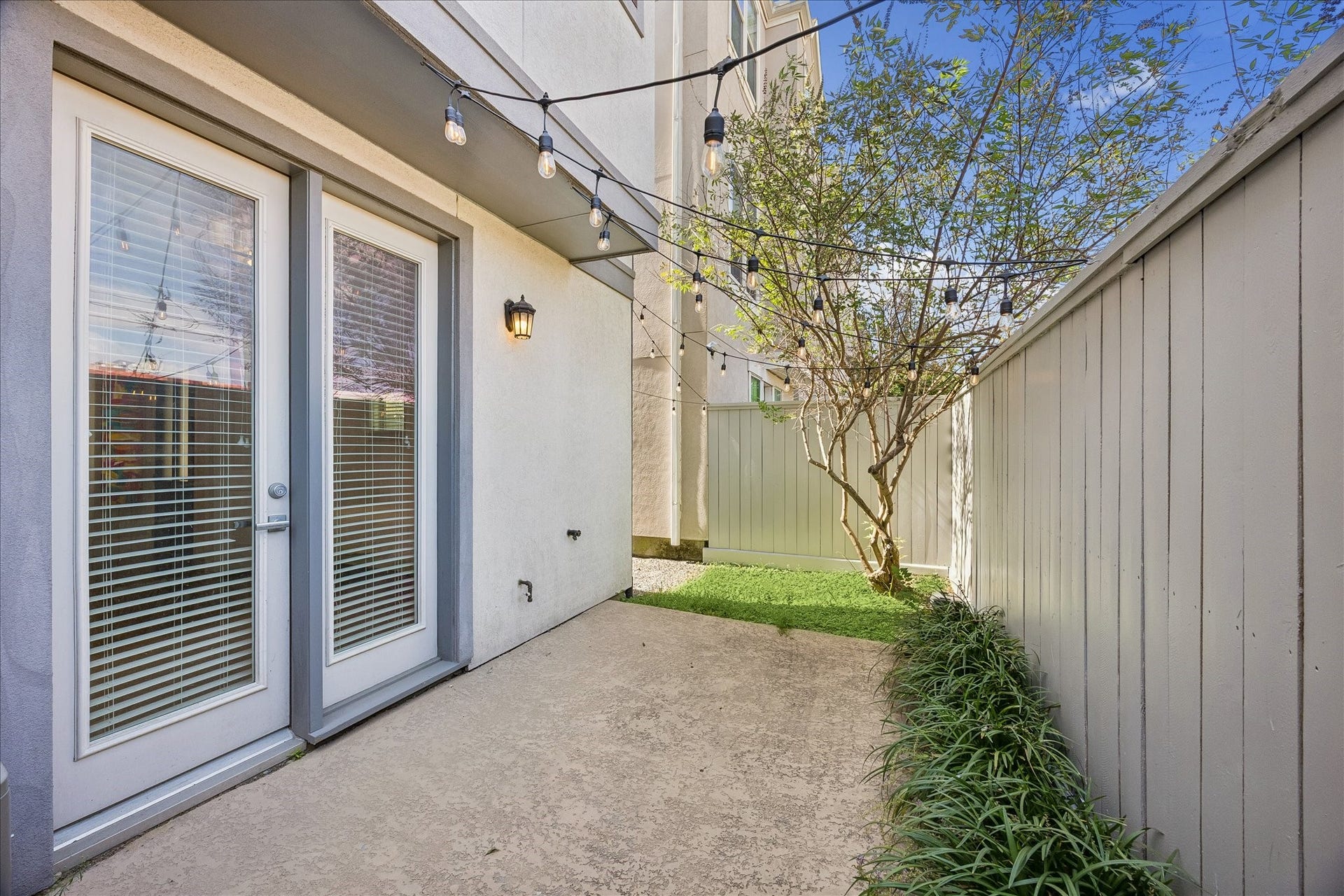 Charming private backyard offering a wonderful extension of the home's living spaces! Patio area w/ string lights provides a lovely setting for dining al fresco, grilling & entertaining. Fully fenced w/ graveled side yard, green space & convenient access through side gate or 1st floor guest suite. Grass space for pets. Exterior fence freshly painted Oct. '26! Gutters & sprinkler system add everyday convenience. Patio string lights included!