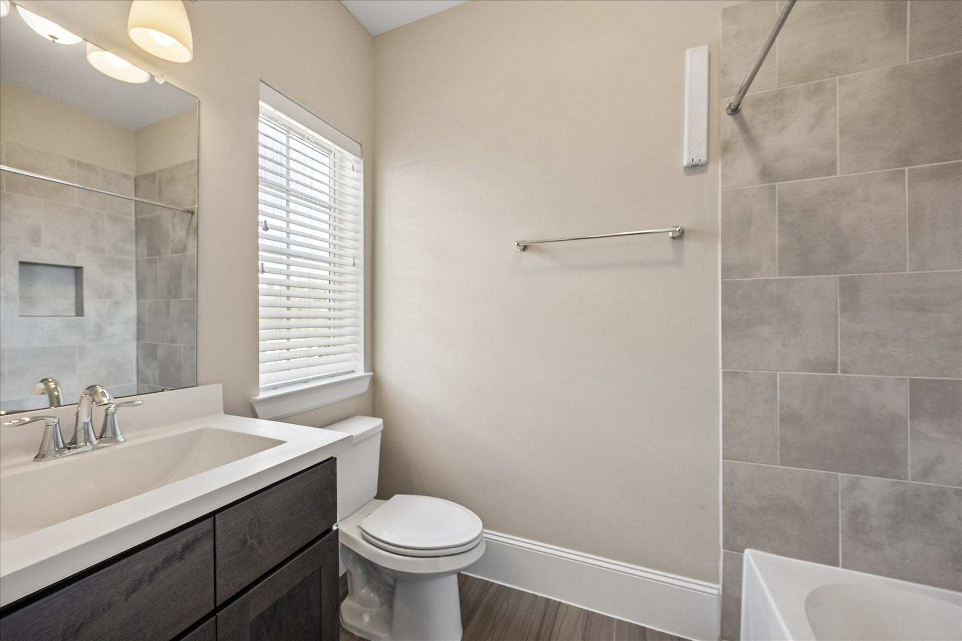 Private en suite bath conveniently serving the 3rd floor secondary bedroom features vanity, shower/tub combination w/ built-in soap niche & window w/ blinds providing natural light. Wonderful functionality for guests or everyday use, while the adjoining bedroom offers flexibility as a home office or additional guest suite!