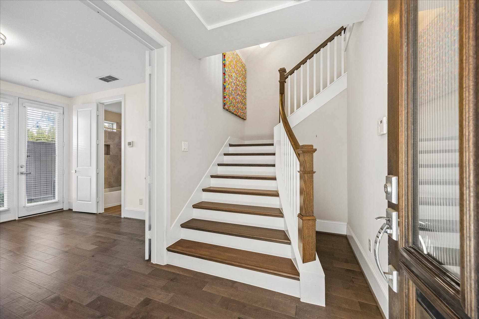 Welcoming 1st floor entry featuring decorative pendant lighting, staircase w/ beautiful light fixtures & convenient access to attached 2-car garage on the right. Double doors  on your left lead to spacious 1st floor secondary bedroom w/ private en suite bath & walk-in closet. Flexible guest bedroom could also make an ideal home office, gym; you name it! Staircase leads to the expansive 2nd floor living spaces!