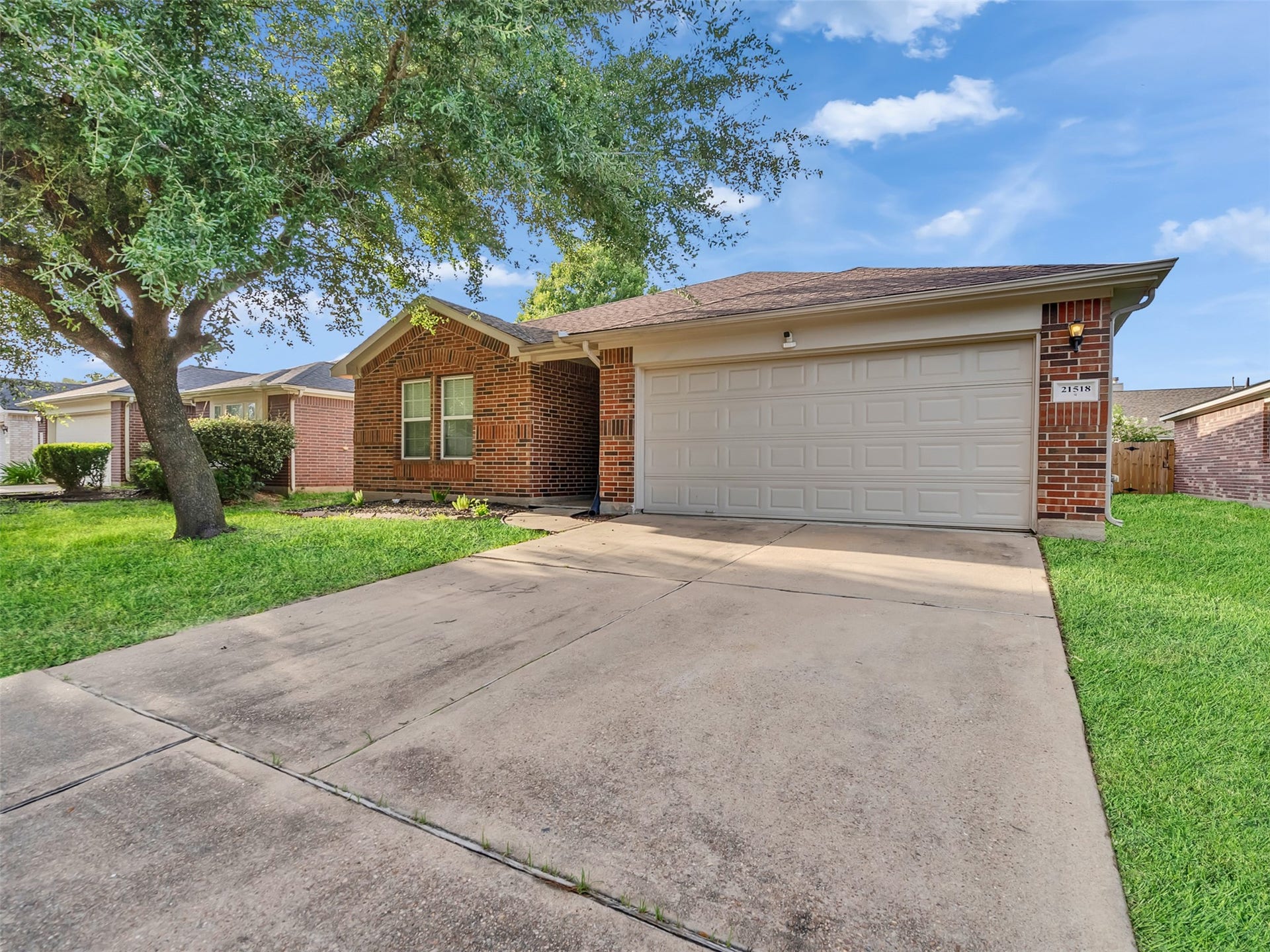 21518 Gannet Peak Way, Katy, TX 77449 Charming brick home with a two-car garage, nestled in a well-maintained neighborhood. The front yard features a mature tree and a spacious driveway.
