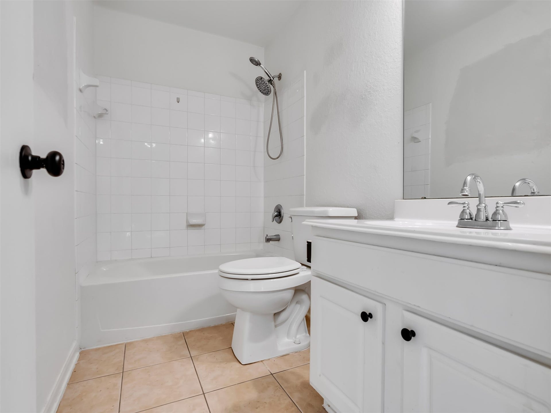 21518 Gannet Peak Way, Katy, TX 77449 This is a clean, white bathroom featuring a bathtub with shower, tile flooring, and a vanity with a modern faucet.
