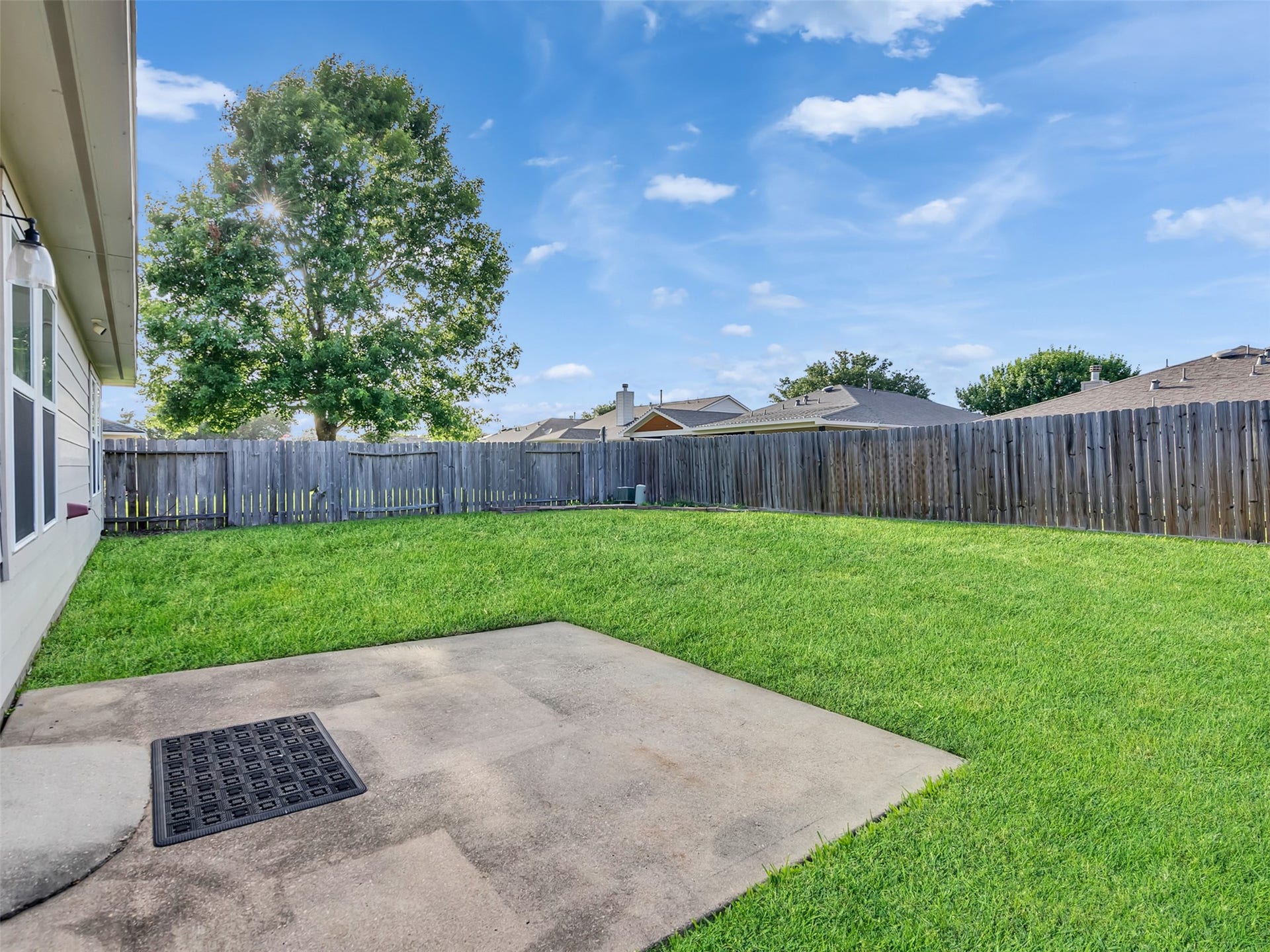 21518 Gannet Peak Way, Katy, TX 77449 Spacious backyard featuring a well-maintained lawn, a concrete patio, and a wooden privacy fence, ideal for outdoor activities and relaxation.