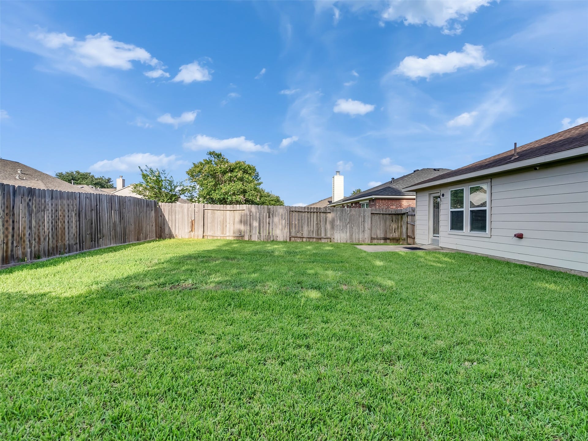 21518 Gannet Peak Way, Katy, TX 77449 Spacious backyard with well-maintained grass, surrounded by a wooden fence for privacy. Ideal for outdoor activities and relaxation.