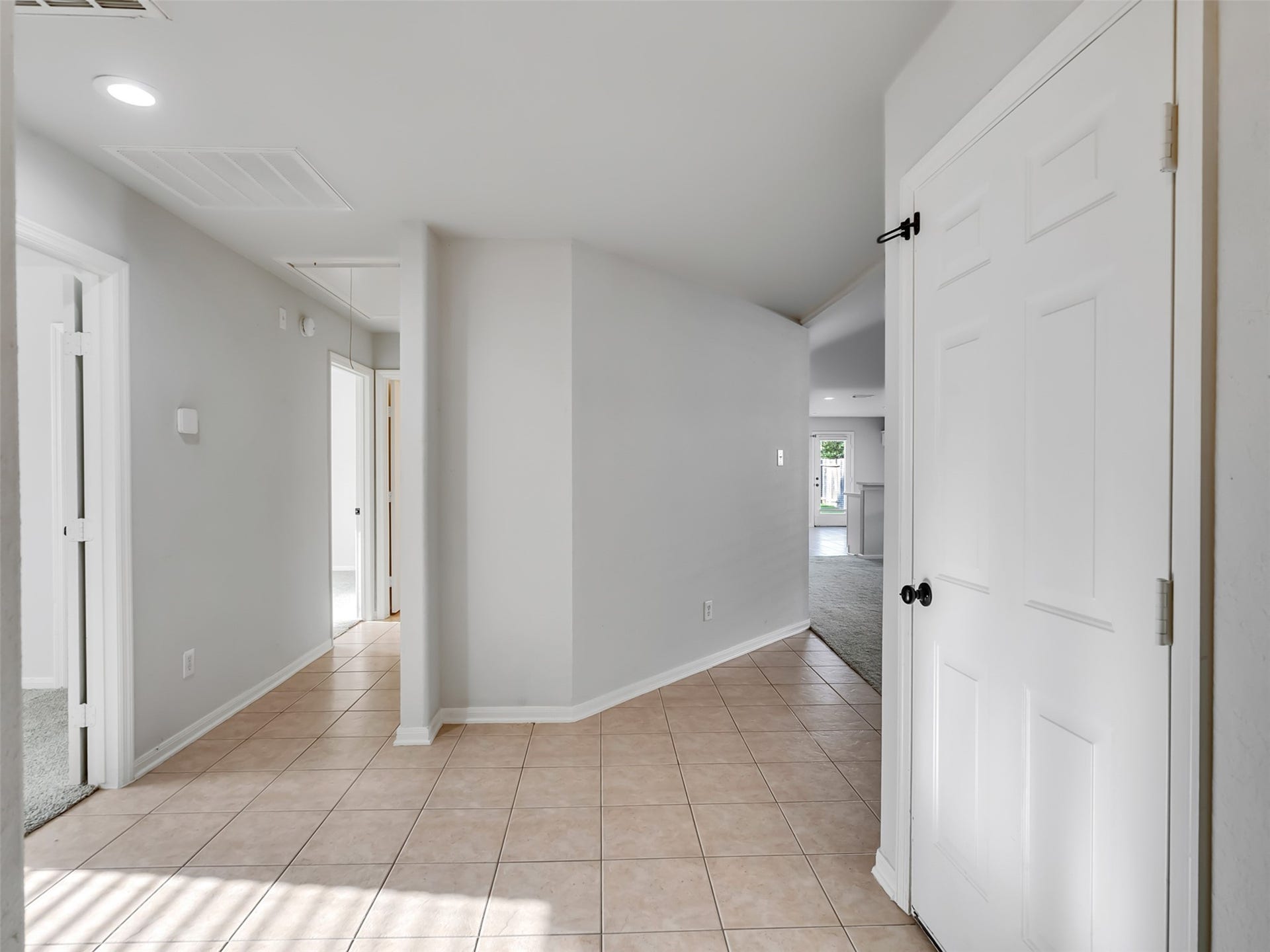 21518 Gannet Peak Way, Katy, TX 77449 A bright hallway with tiled flooring, neutral walls, and several doors leading to different rooms. The space appears open and inviting with natural light streaming in.