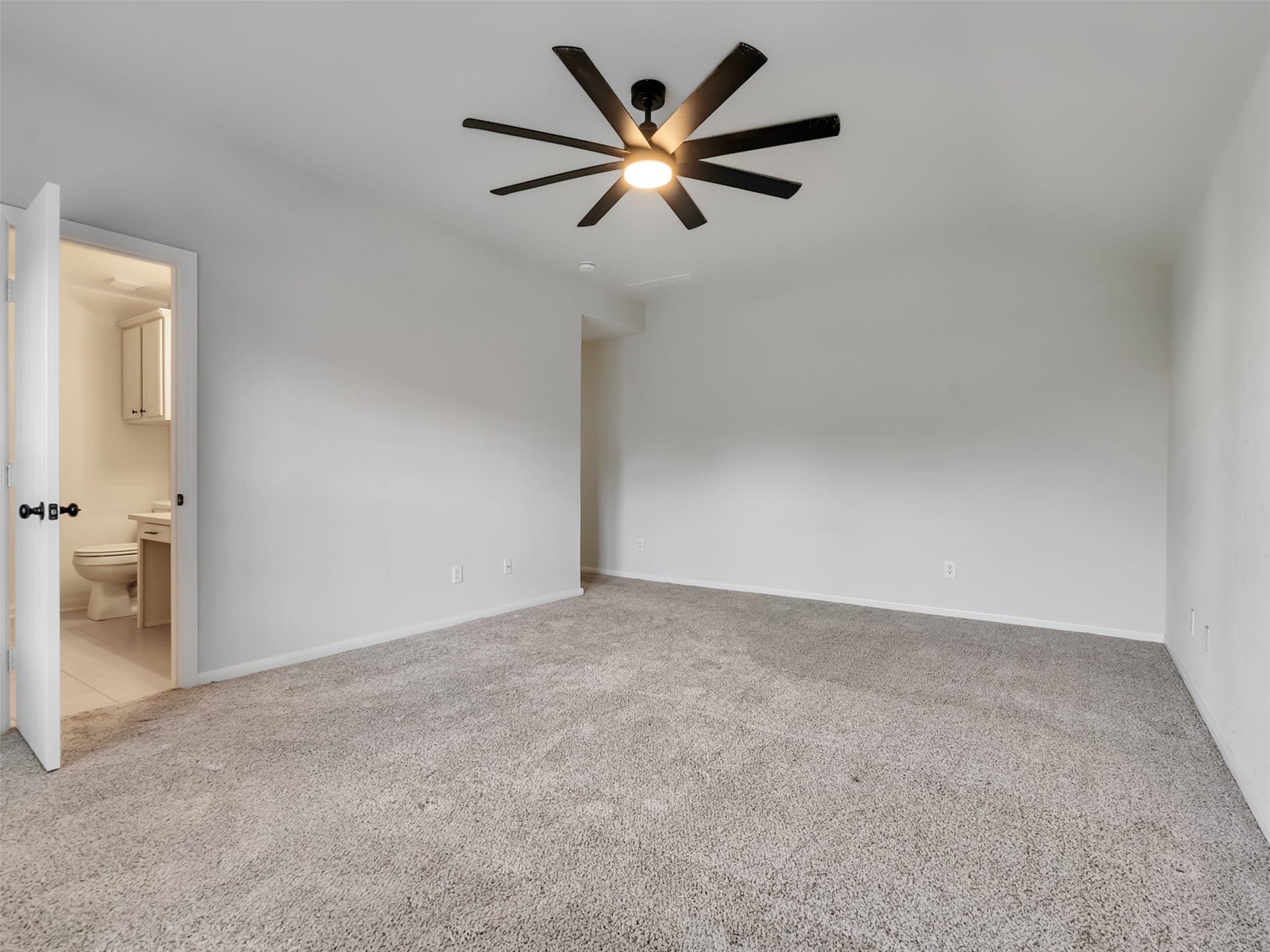 21518 Gannet Peak Way, Katy, TX 77449 Spacious bedroom with plush carpet, neutral walls, a modern ceiling fan, and an en-suite bathroom.