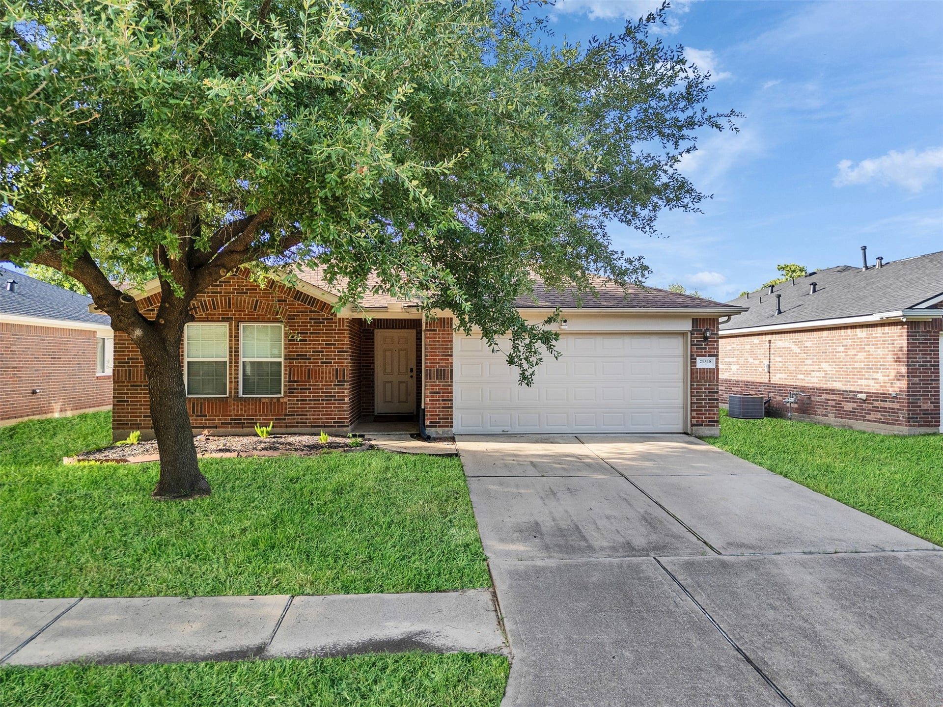 21518 Gannet Peak Way, Katy, TX 77449 Charming single-story brick home with a two-car garage and a welcoming front yard featuring a mature tree, providing shade and curb appeal.