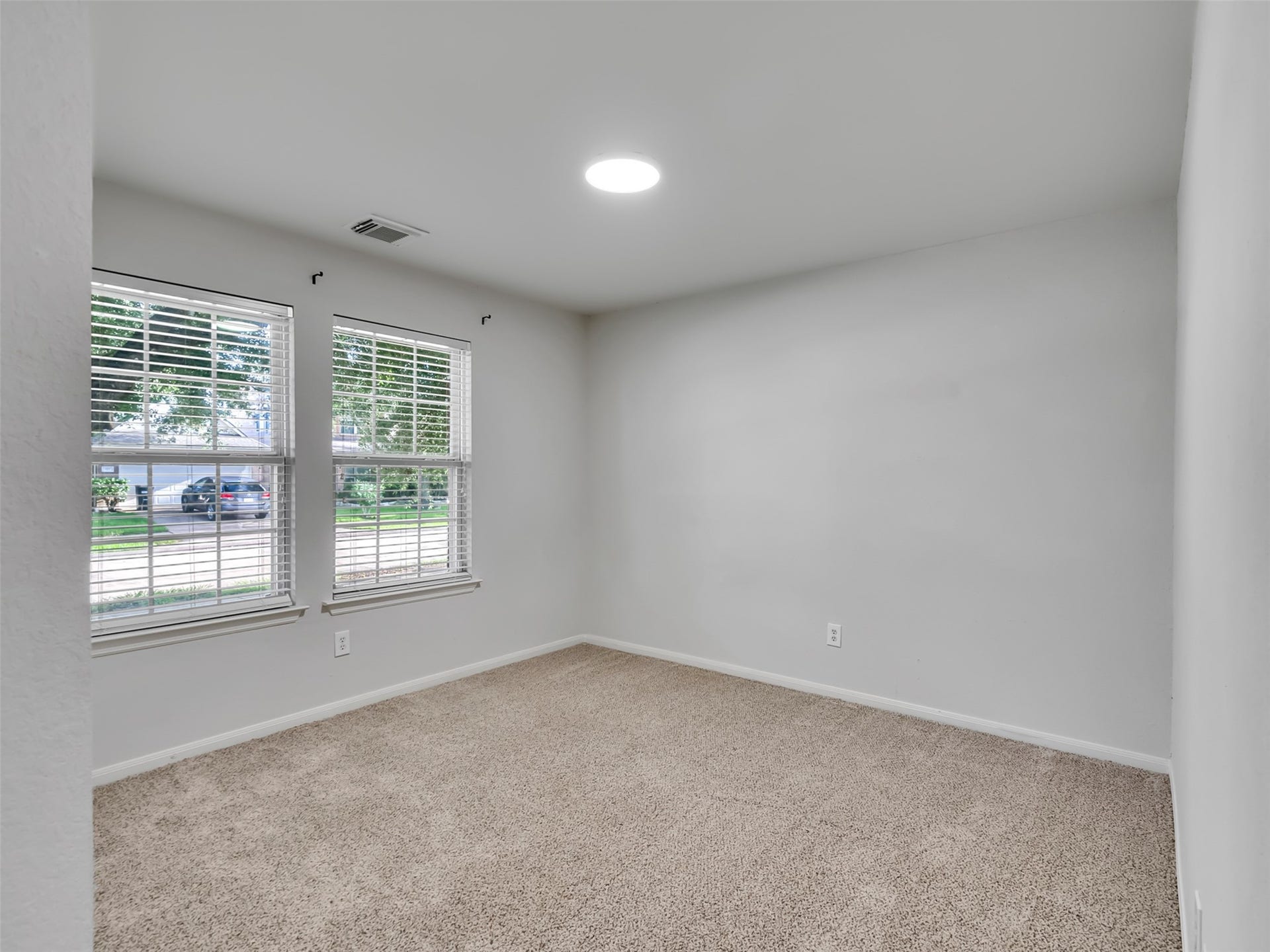 21518 Gannet Peak Way, Katy, TX 77449 This room features neutral carpeting, light gray walls, and two large windows that provide ample natural light. It's a versatile space that can be used as a bedroom or home office.