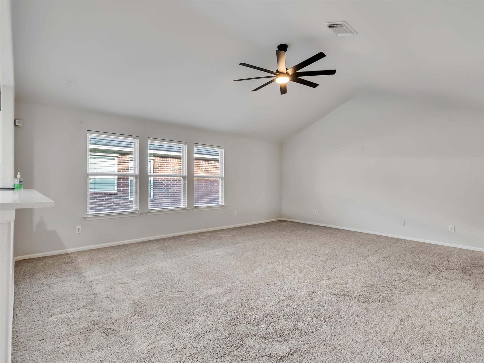 21518 Gannet Peak Way, Katy, TX 77449 This spacious room features high ceilings, a modern ceiling fan, and plush carpet flooring. Natural light streams through three large windows, creating a bright and airy atmosphere. Perfect for relaxation or entertaining.