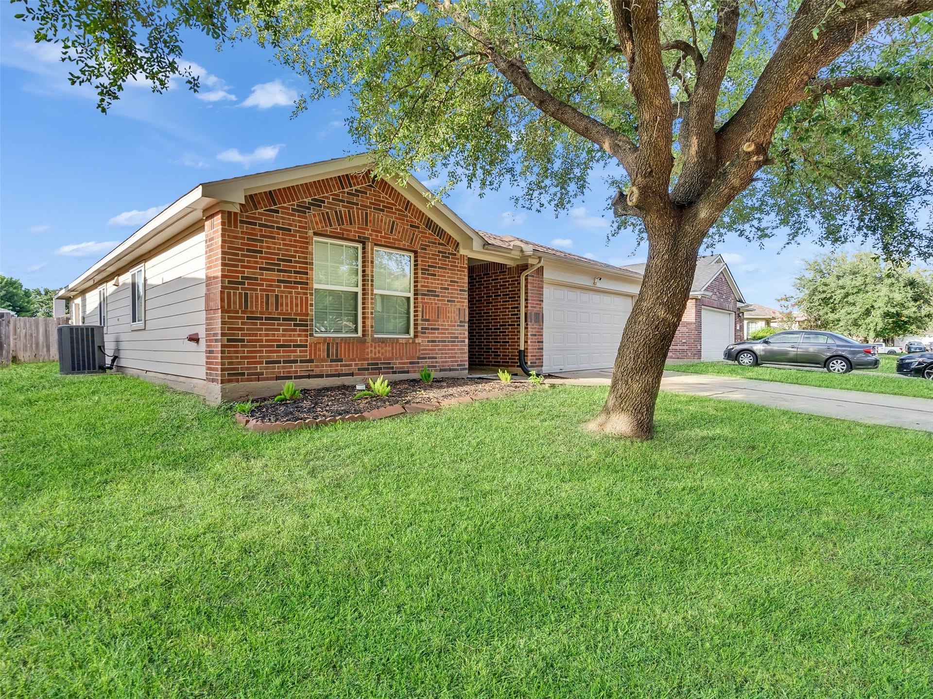 21518 Gannet Peak Way, Katy, TX 77449 A charming brick home with a two-car garage, set on a well-maintained lawn. A mature tree offers shade, enhancing the property's curb appeal.