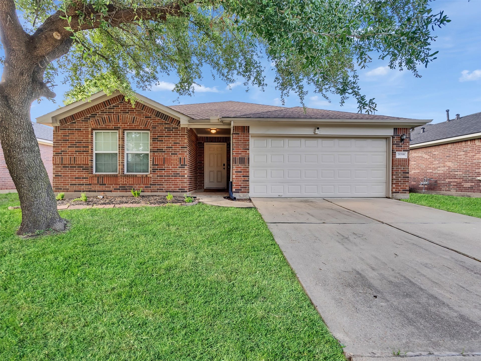 21518 Gannet Peak Way, Katy, TX 77449 Featuring a charming single-story brick home with a well-maintained front lawn. It includes a spacious two-car garage and a welcoming entryway. The property is shaded by a large tree, adding to its curb appeal.