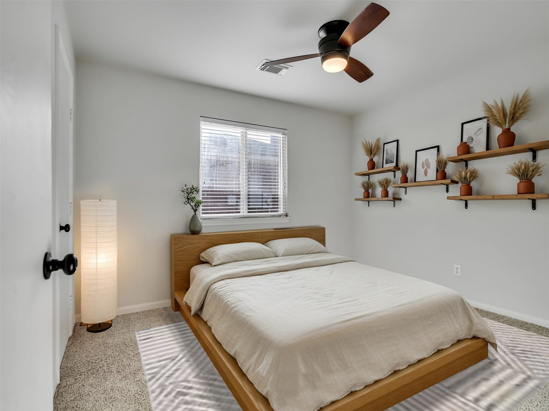 21518 Gannet Peak Way, Katy, TX 77449 This cozy bedroom features a modern design with a wooden bed frame, neutral bedding, and a ceiling fan. It has a window for natural light and decorative shelves with plants and artwork, creating a serene atmosphere.